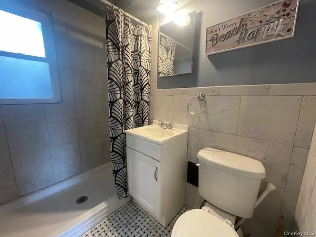 Full bath featuring a shower stall, vanity, and tile walls Full bath featuring a shower stall, vanity, and tile walls