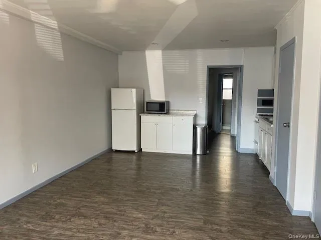 Kitchen with white cabinets, appliances with stainless steel finishes, light countertops, and dark wood-type flooring Kitchen with white cabinets, appliances with stainless steel finishes, light countertops, and dark wood-type flooring