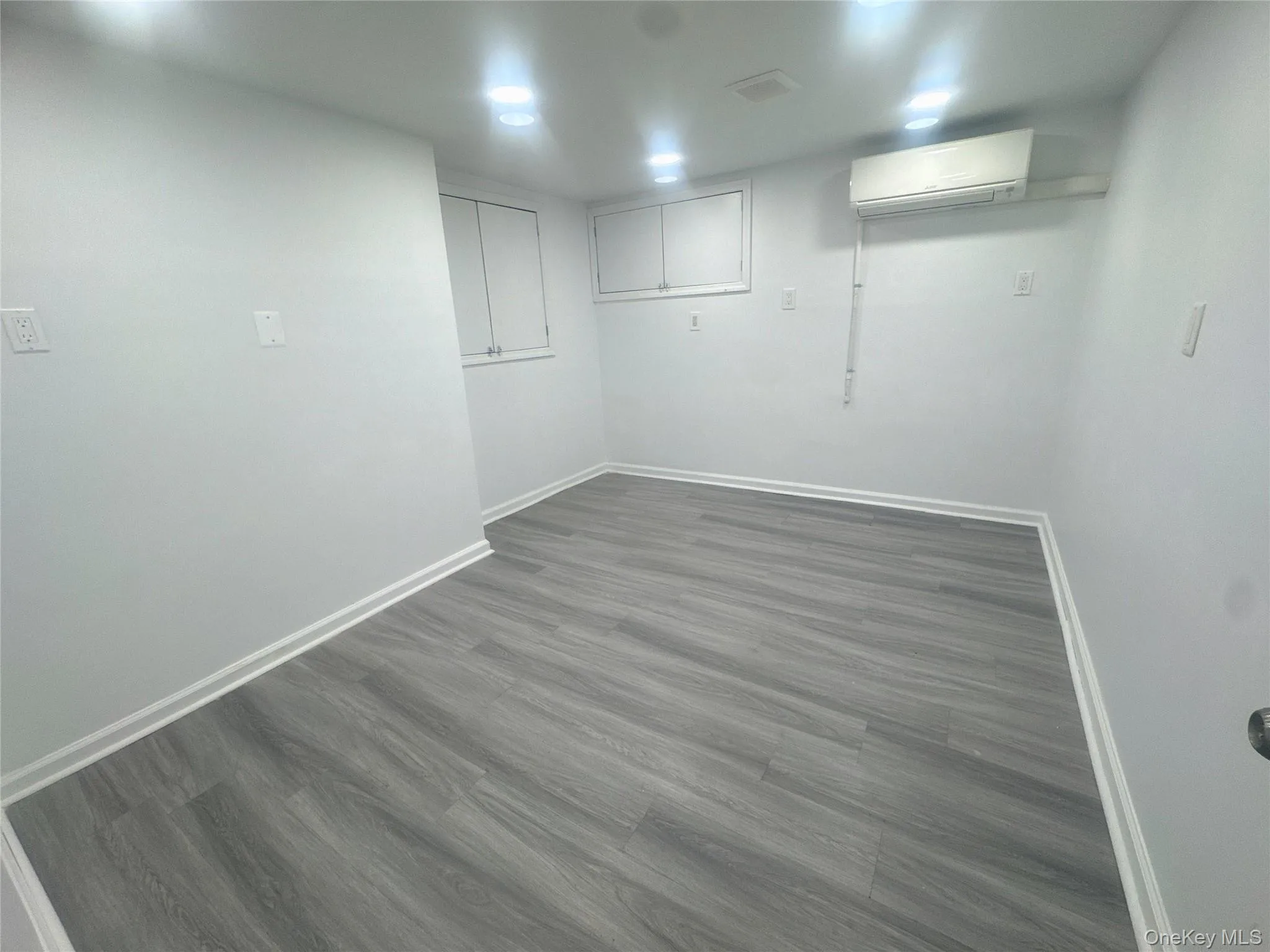 Finished below grade area with dark wood-style flooring and a wall mounted AC Finished below grade area with dark wood-style flooring and a wall mounted AC