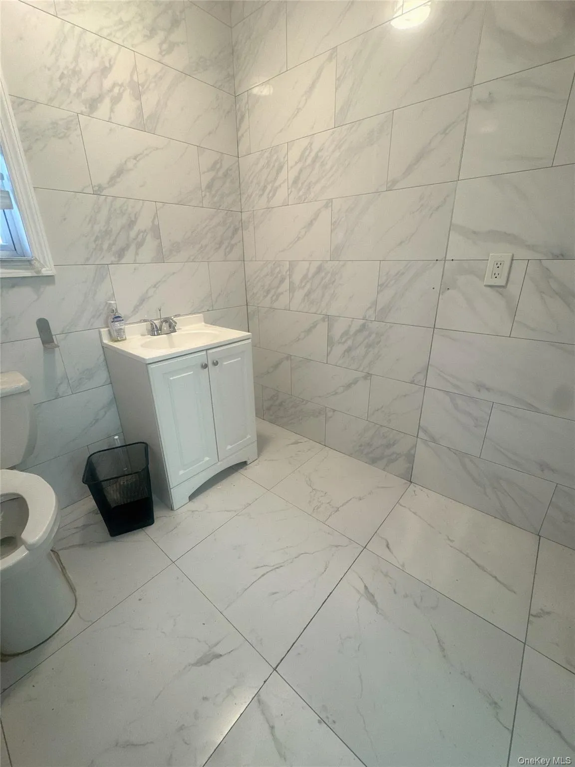 Bathroom featuring tile walls, light marble finish floors, and vanity Bathroom featuring tile walls, light marble finish floors, and vanity