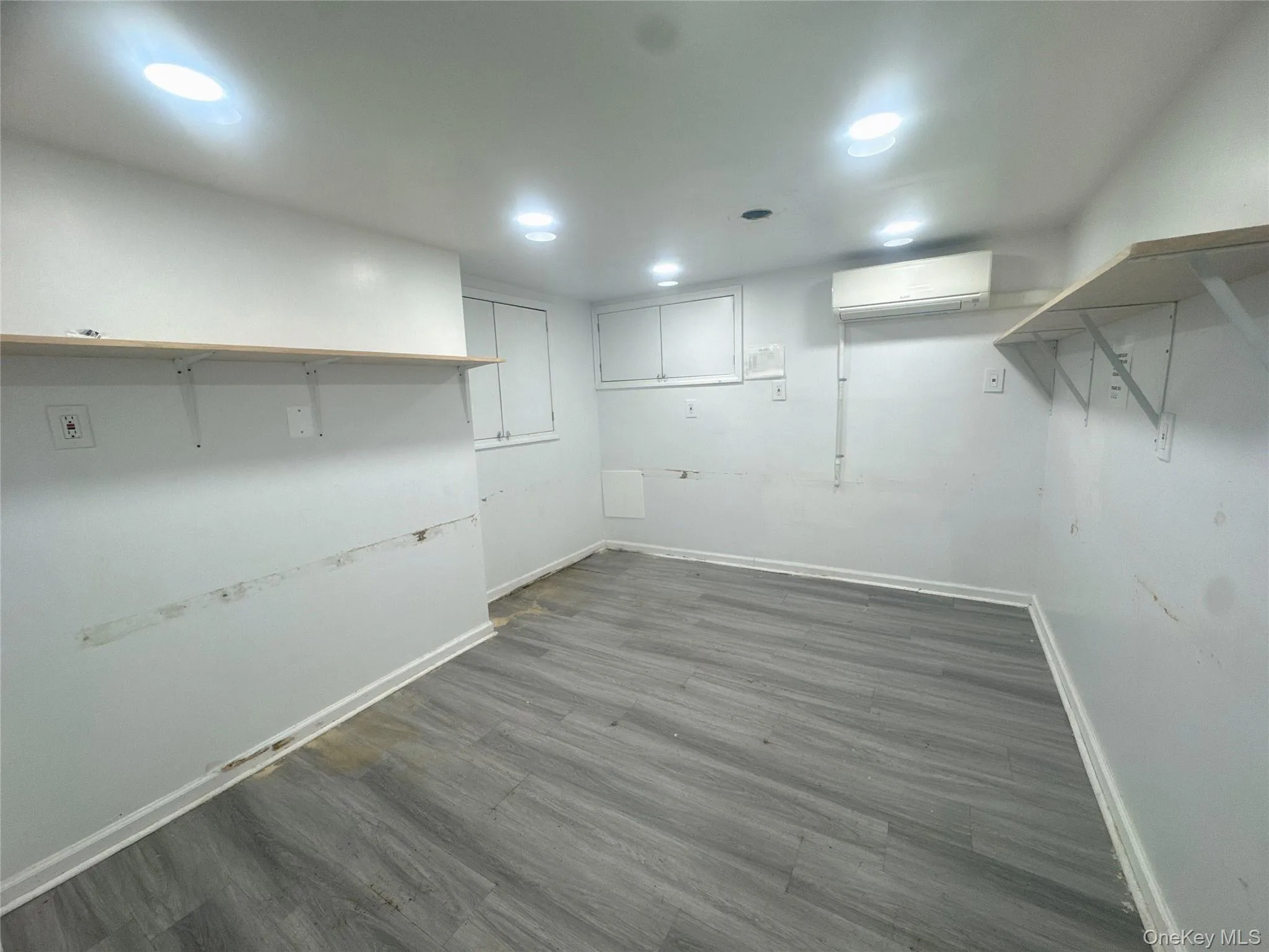 Finished below grade area featuring dark wood-style floors and a wall mounted air conditioner Finished below grade area featuring dark wood-style floors and a wall mounted air conditioner