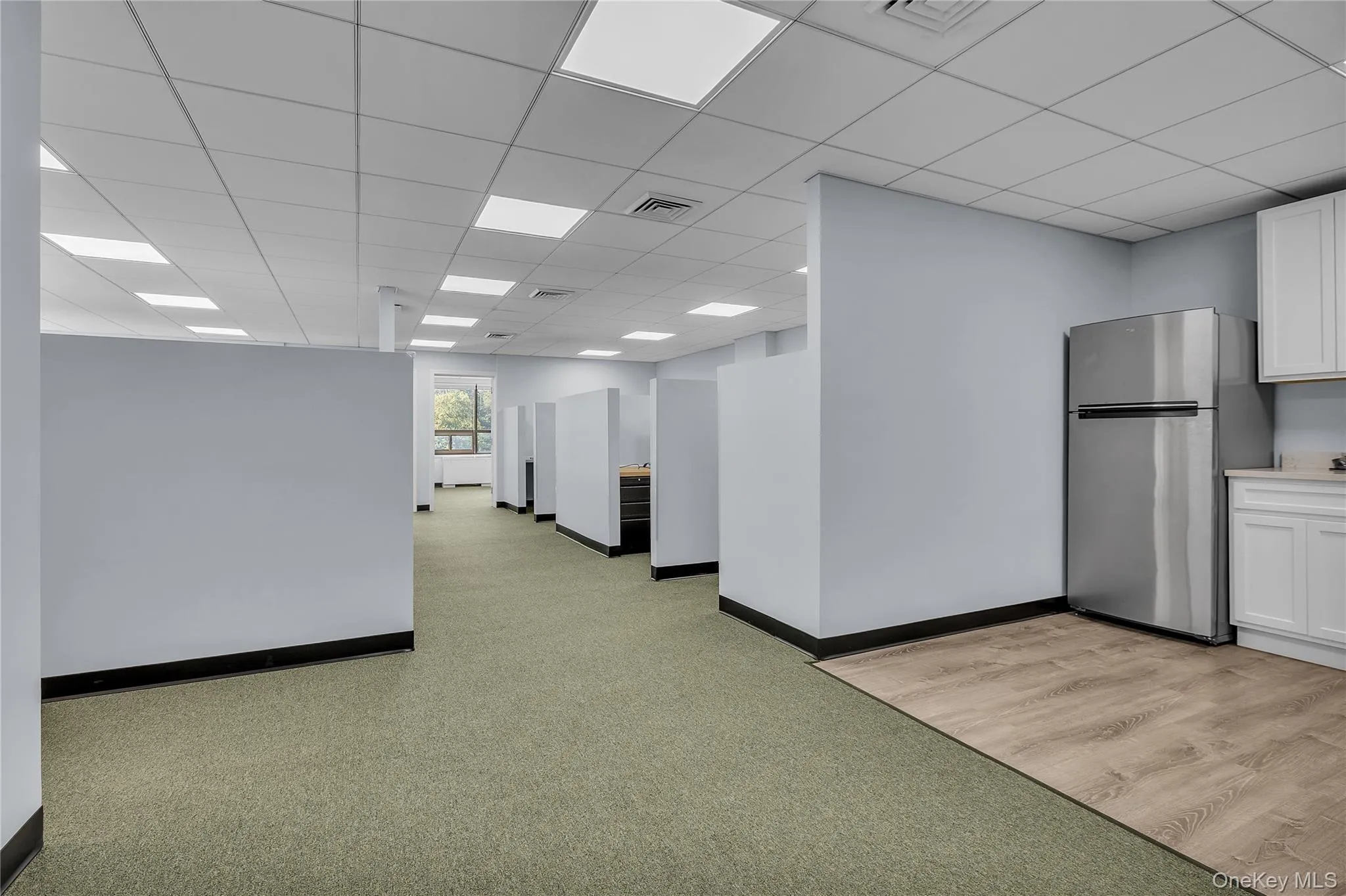 Empty room with a drop ceiling and light colored carpet Empty room with a drop ceiling and light colored carpet