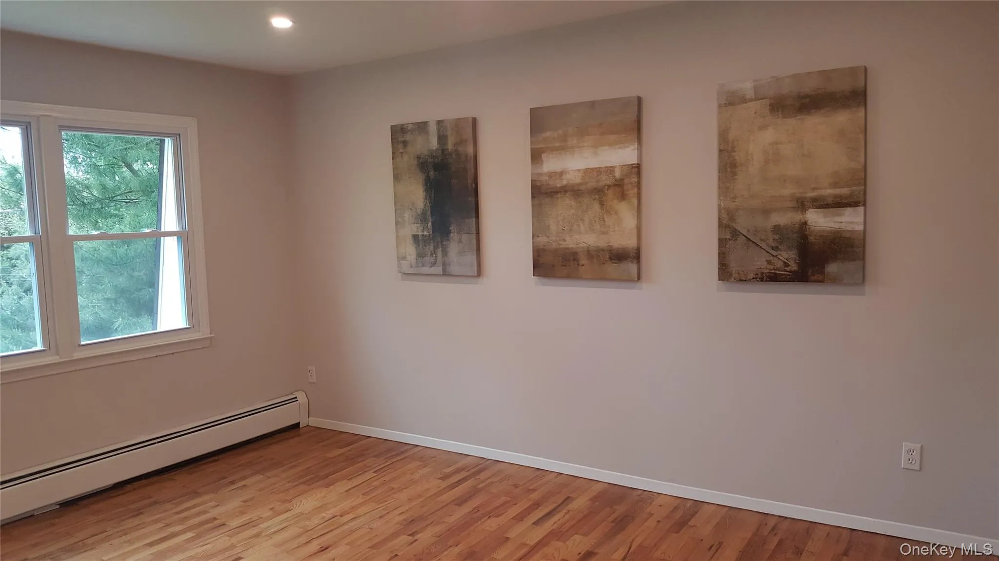 Empty room featuring a baseboard radiator and light wood finished floors Empty room featuring a baseboard radiator and light wood finished floors