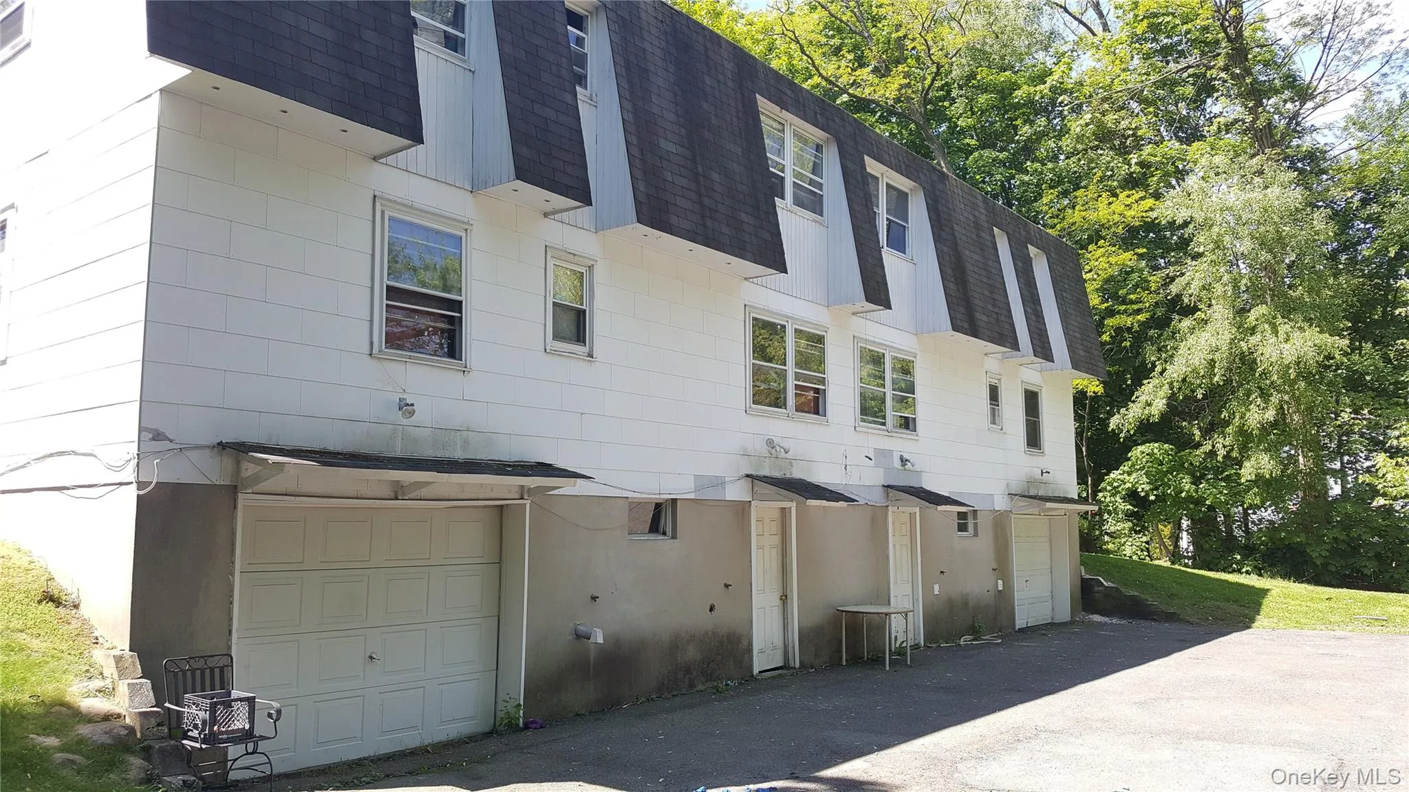 View of side of home with roof with shingles, mansard roof, and an attached garage View of side of home with roof with shingles, mansard roof, and an attached garage