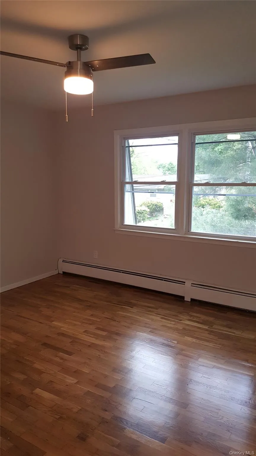 Empty room featuring a baseboard radiator and dark wood-type flooring Empty room featuring a baseboard radiator and dark wood-type flooring