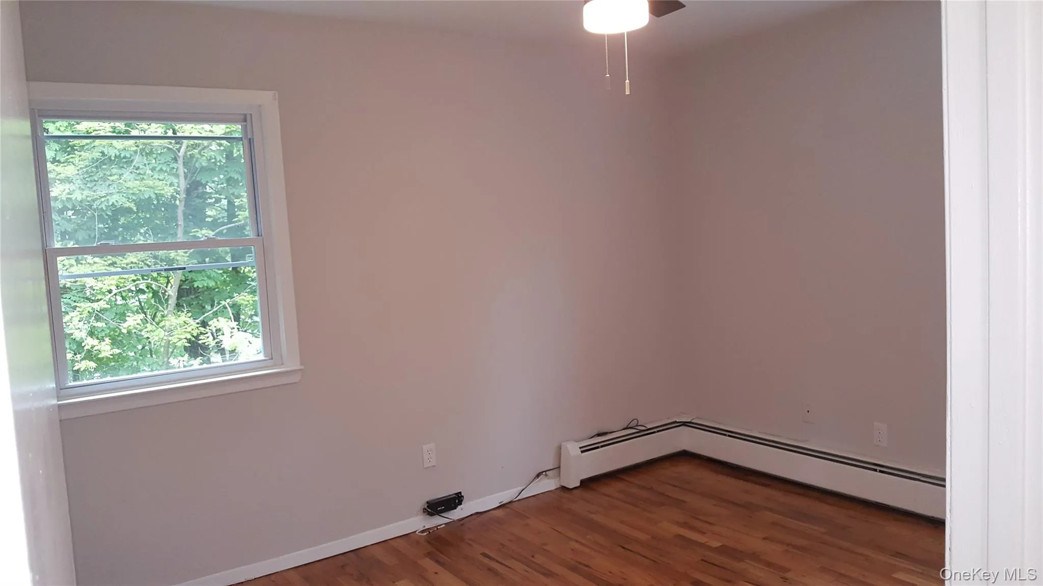 Spare room with dark wood-style floors and baseboards Spare room with dark wood-style floors and baseboards