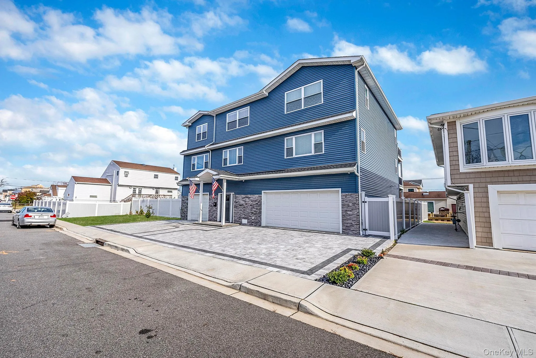 Traditional-style home with decorative driveway, stone siding, a garage, and a residential view Traditional-style home with decorative driveway, stone siding, a garage, and a residential view