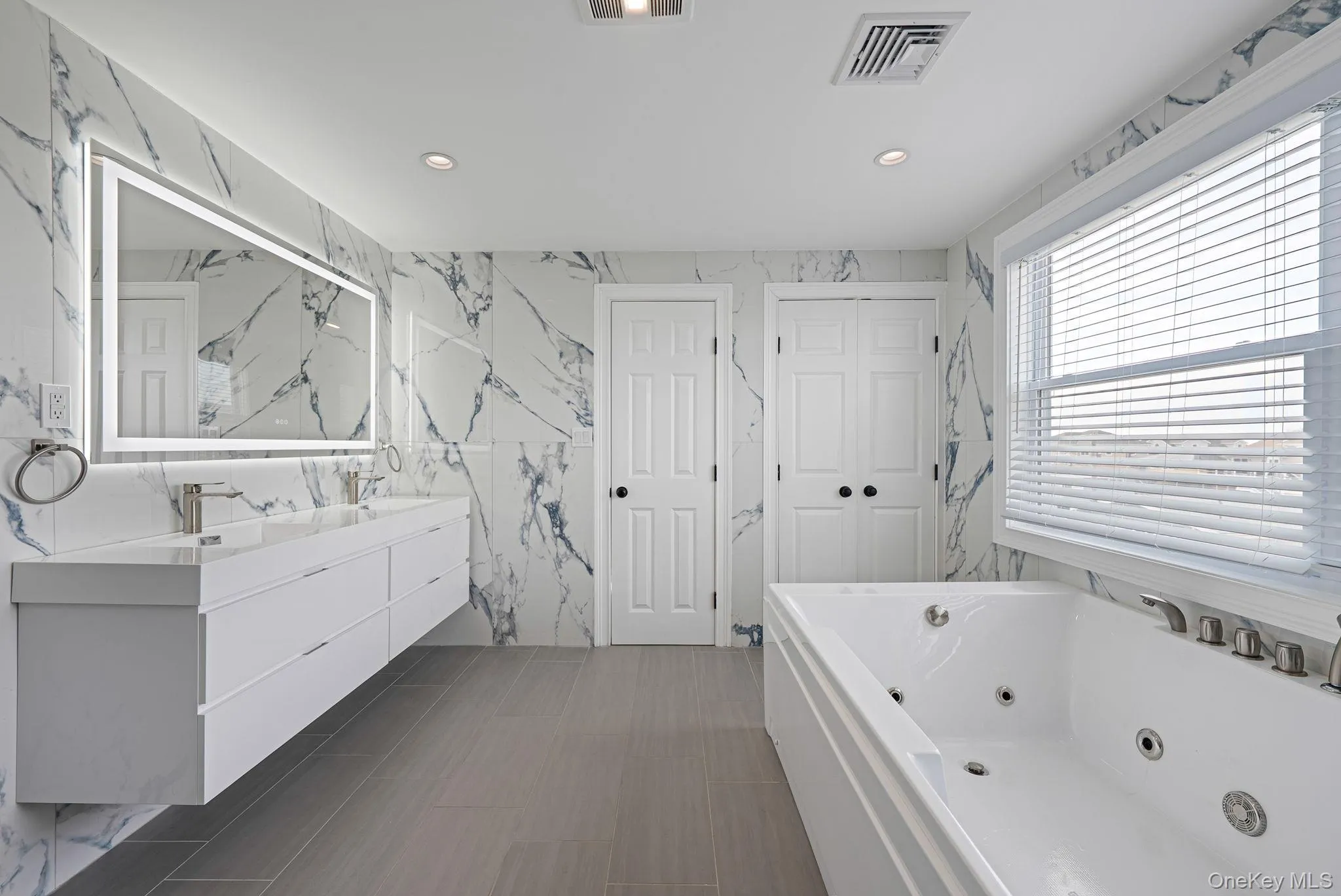 Bathroom with stone wall, a whirlpool tub, double vanity, recessed lighting, and tile walls Bathroom with stone wall, a whirlpool tub, double vanity, recessed lighting, and tile walls