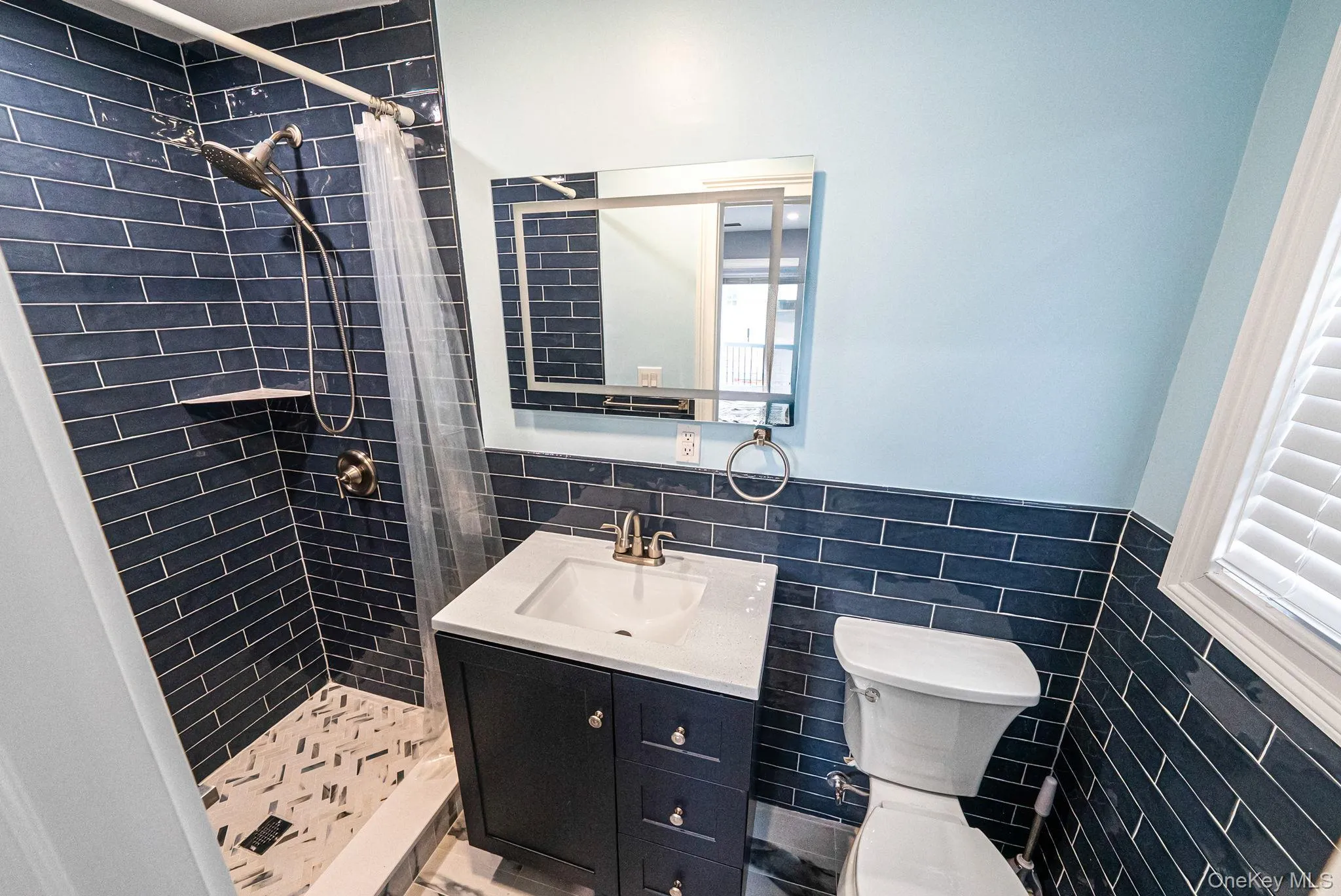 Bathroom featuring tile walls, a shower stall, vanity, and wainscoting Bathroom featuring tile walls, a shower stall, vanity, and wainscoting