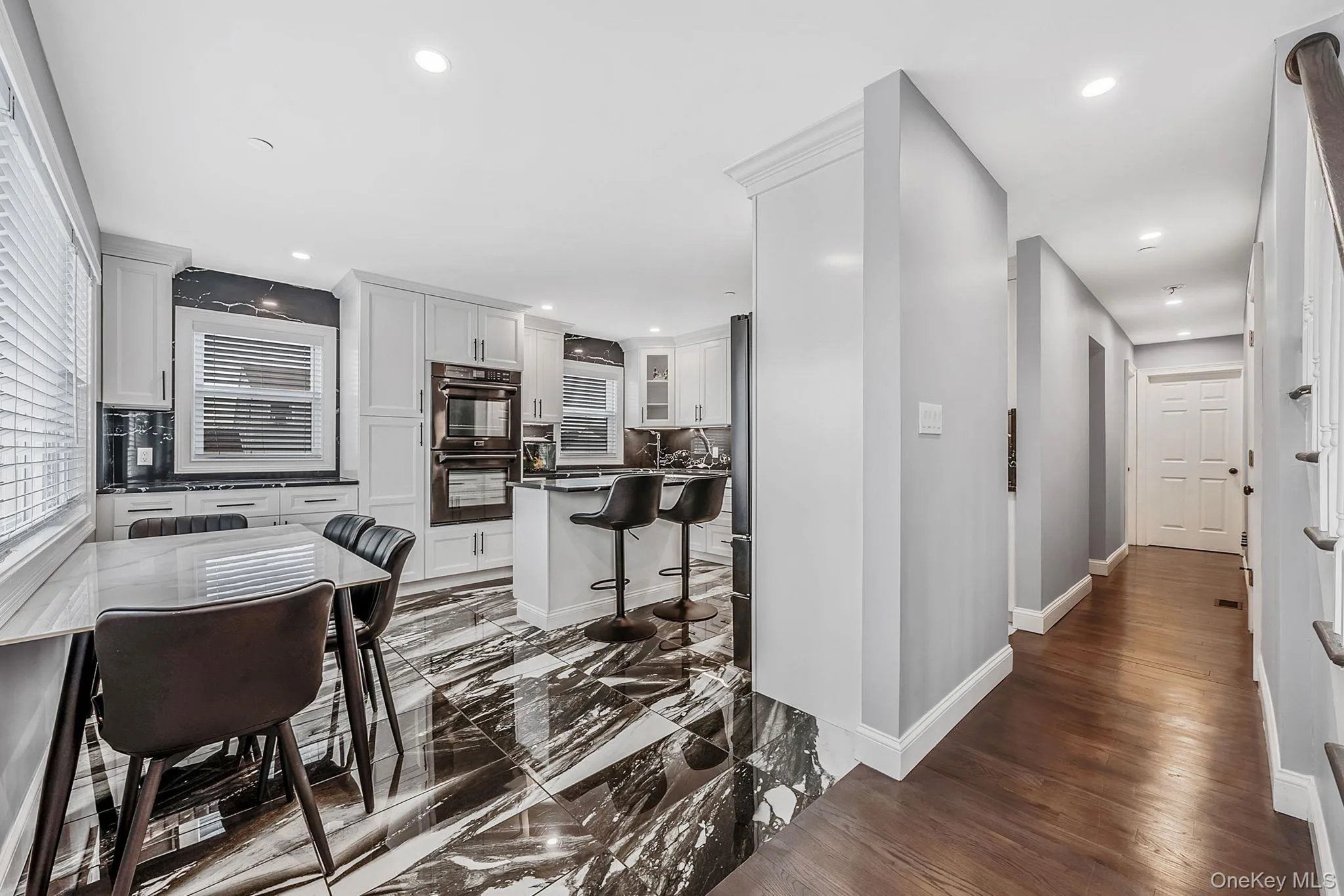 Kitchen featuring a breakfast bar area, white cabinets, backsplash, refrigerator, and recessed lighting Kitchen featuring a breakfast bar area, white cabinets, backsplash, refrigerator, and recessed lighting