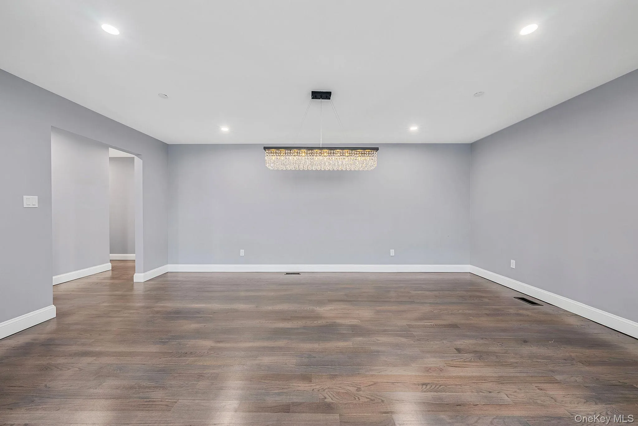 Spare room featuring recessed lighting, dark wood-style flooring, and a chandelier Spare room featuring recessed lighting, dark wood-style flooring, and a chandelier