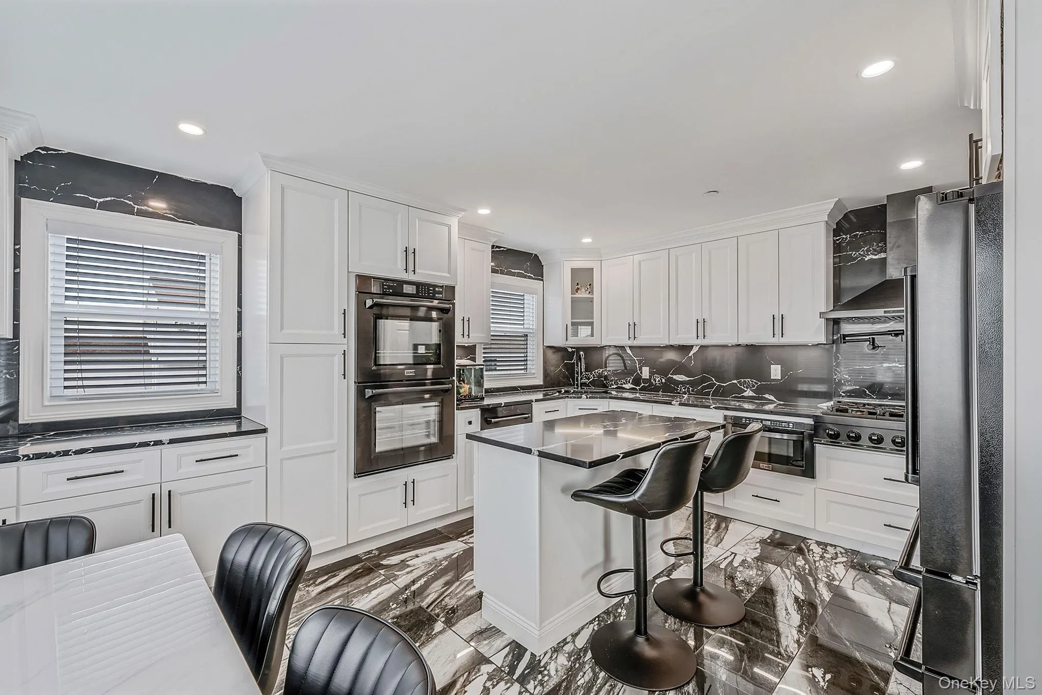Kitchen with a breakfast bar area, stainless steel appliances, tasteful backsplash, dark marble finish floors, and recessed lighting Kitchen with a breakfast bar area, stainless steel appliances, tasteful backsplash, dark marble finish floors, and recessed lighting