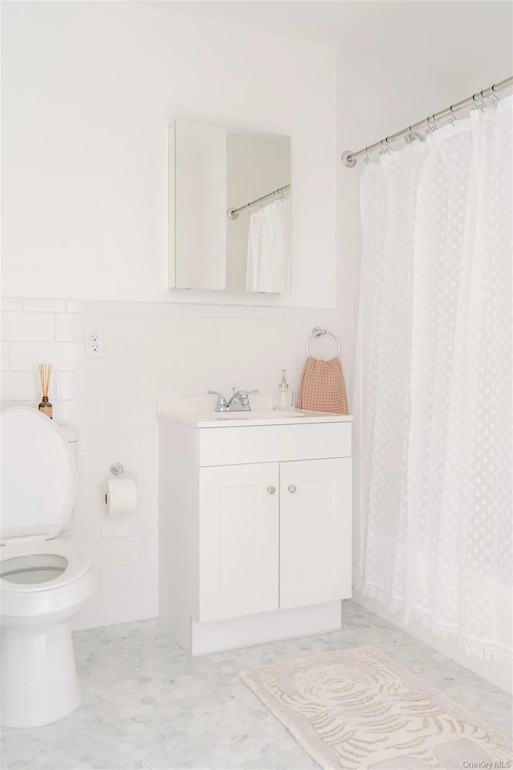 Bathroom with a shower with shower curtain, vanity, tile walls, a wainscoted wall, and light flooring Bathroom with a shower with shower curtain, vanity, tile walls, a wainscoted wall, and light flooring
