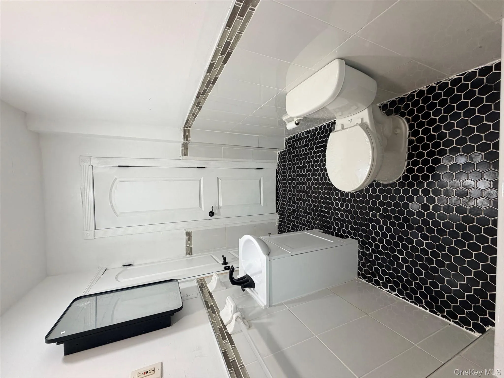 Bathroom with tile walls, a wainscoted wall, vanity, and dark tile patterned flooring Bathroom with tile walls, a wainscoted wall, vanity, and dark tile patterned flooring