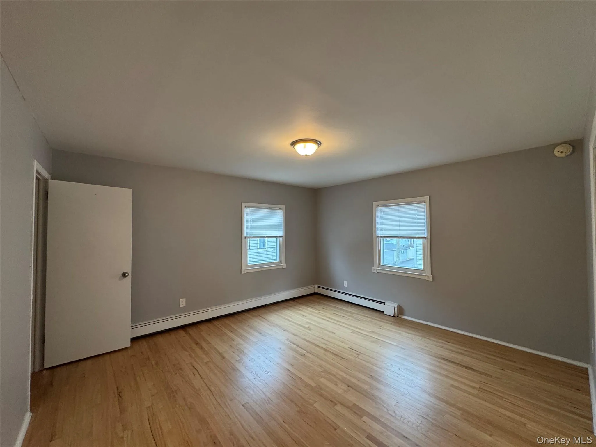 Empty room with light wood-style floors and a baseboard radiator Empty room with light wood-style floors and a baseboard radiator