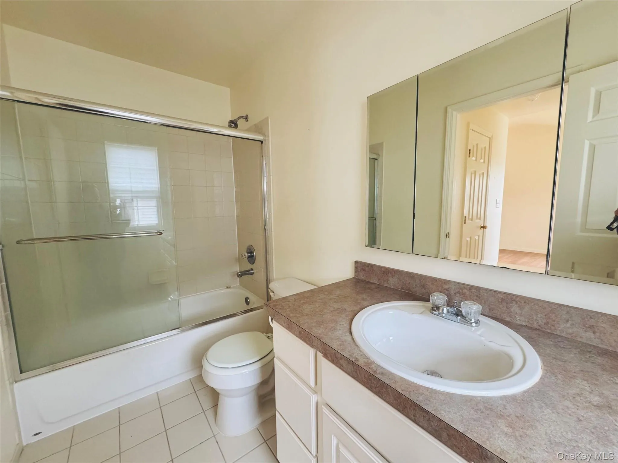 En-Suite Primary Bathroom with shower / bath combination with glass door, vanity, and tiled floors En-Suite Primary Bathroom with shower / bath combination with glass door, vanity, and tiled floors