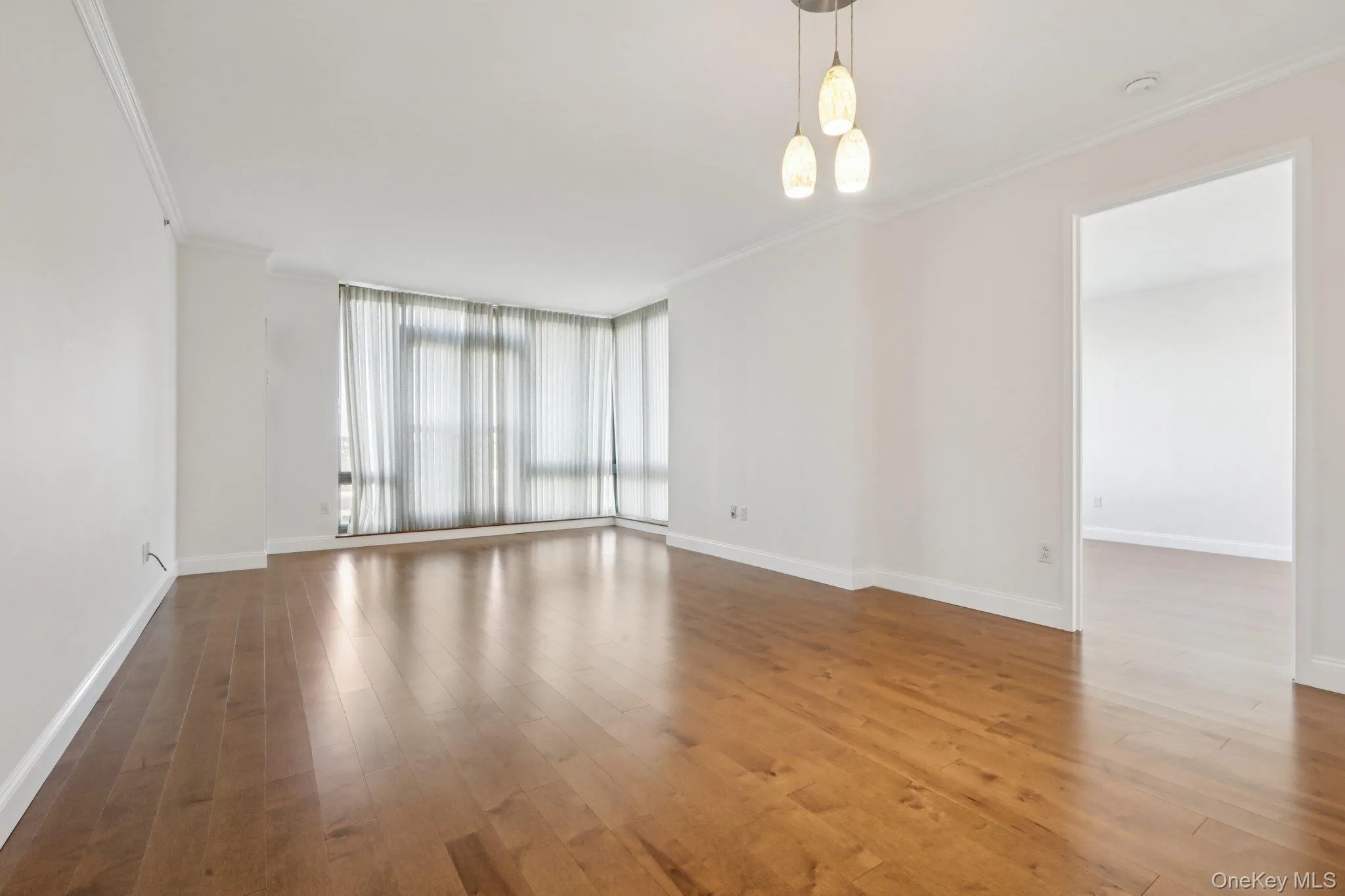 Empty room featuring floor to ceiling windows, crown molding, wood finished floors, and a chandelier Empty room featuring floor to ceiling windows, crown molding, wood finished floors, and a chandelier