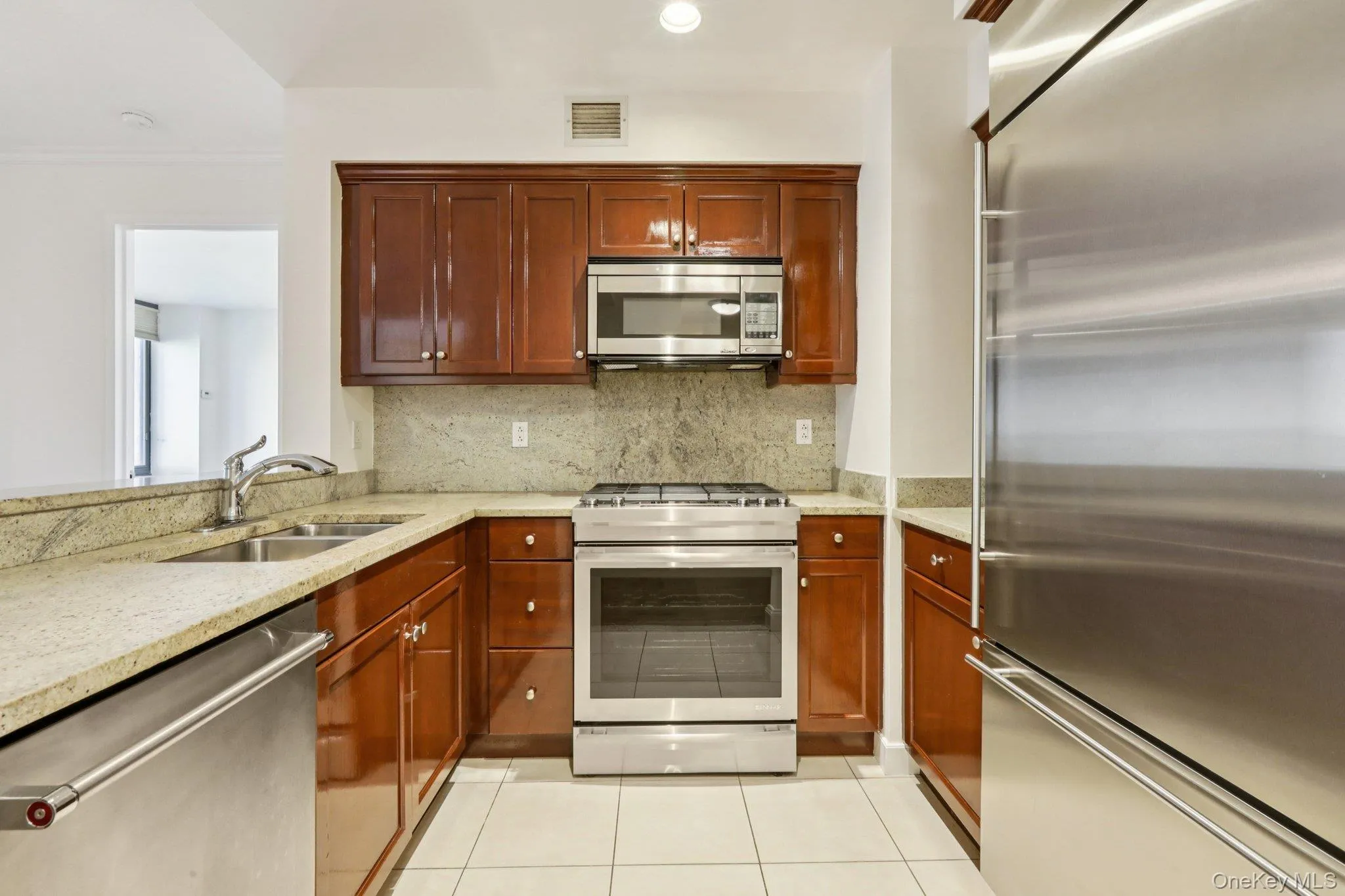 Kitchen featuring appliances with stainless steel finishes, light stone countertops, backsplash, light tile patterned floors, and recessed lighting Kitchen featuring appliances with stainless steel finishes, light stone countertops, backsplash, light tile patterned floors, and recessed lighting