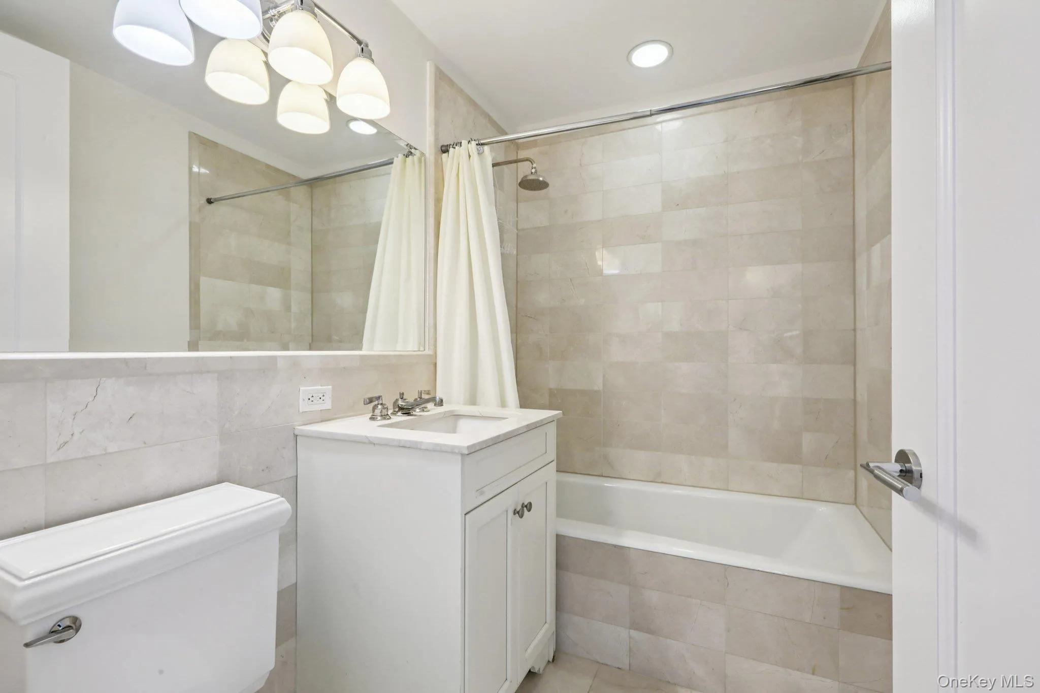 Bathroom featuring tile walls, tiled shower / bath, vanity, and recessed lighting Bathroom featuring tile walls, tiled shower / bath, vanity, and recessed lighting