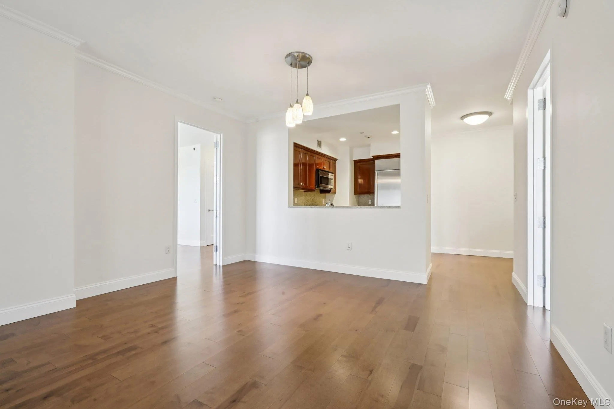 Unfurnished living room featuring dark wood-style flooring and crown molding Unfurnished living room featuring dark wood-style flooring and crown molding