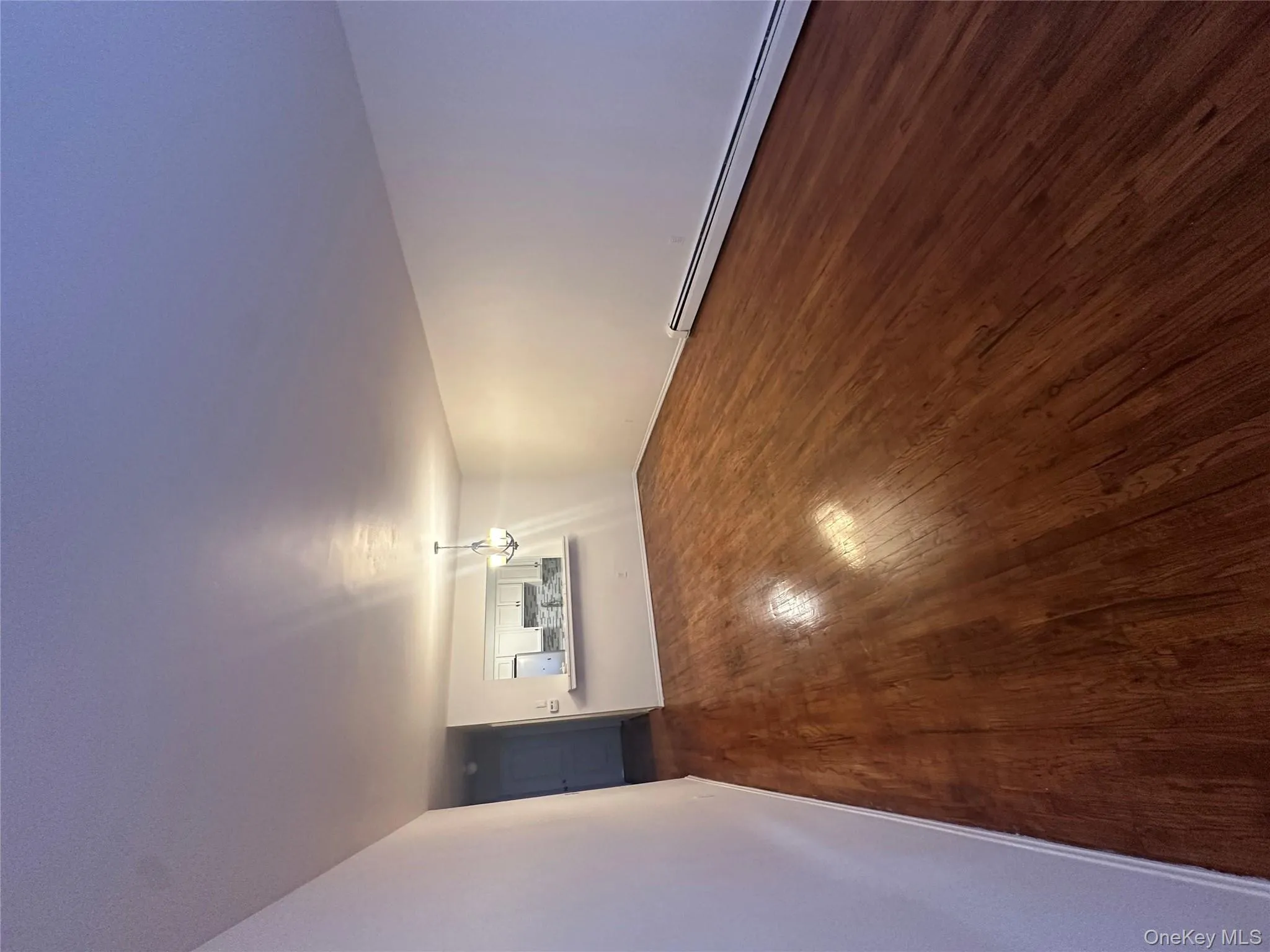 Unfurnished room featuring baseboard heating, a chandelier, and dark wood-style flooring Unfurnished room featuring baseboard heating, a chandelier, and dark wood-style flooring