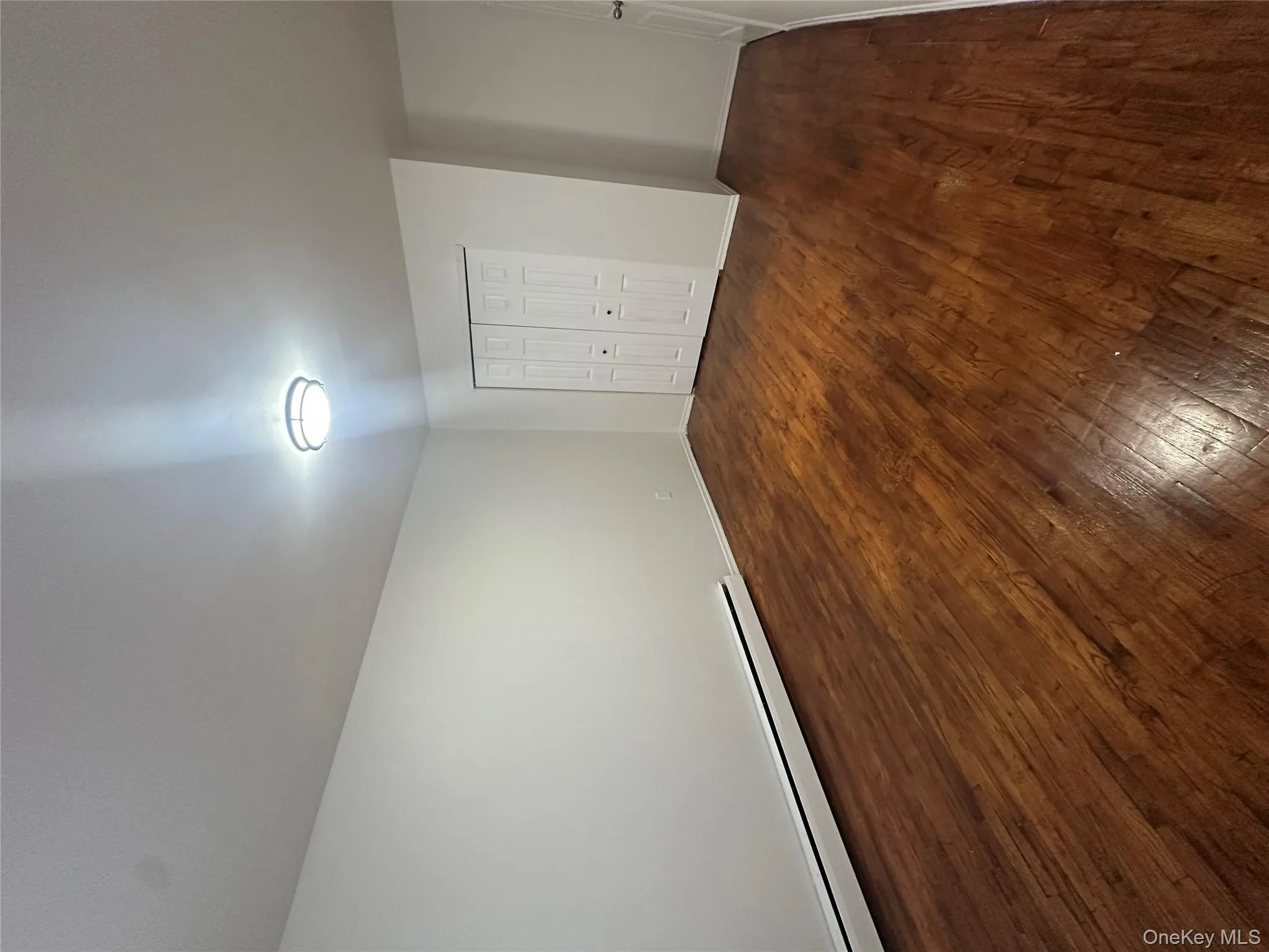 Unfurnished bedroom featuring baseboard heating, dark wood-type flooring, and a closet Unfurnished bedroom featuring baseboard heating, dark wood-type flooring, and a closet