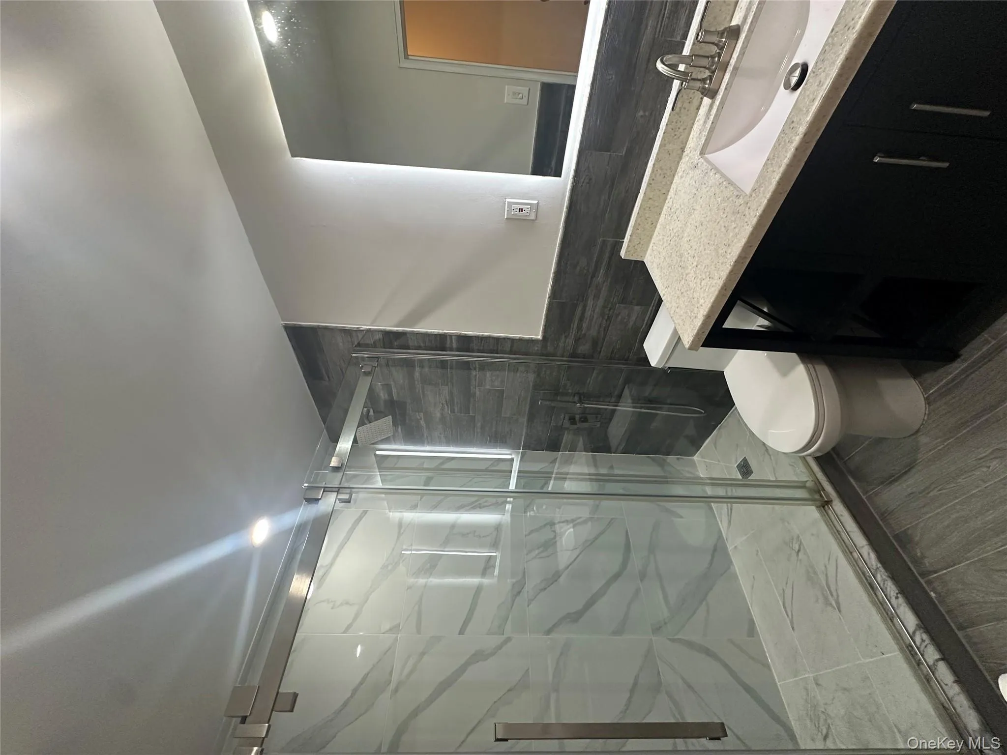 Full bath featuring vanity, tile walls, a marble finish shower, and wood tiled floors Full bath featuring vanity, tile walls, a marble finish shower, and wood tiled floors