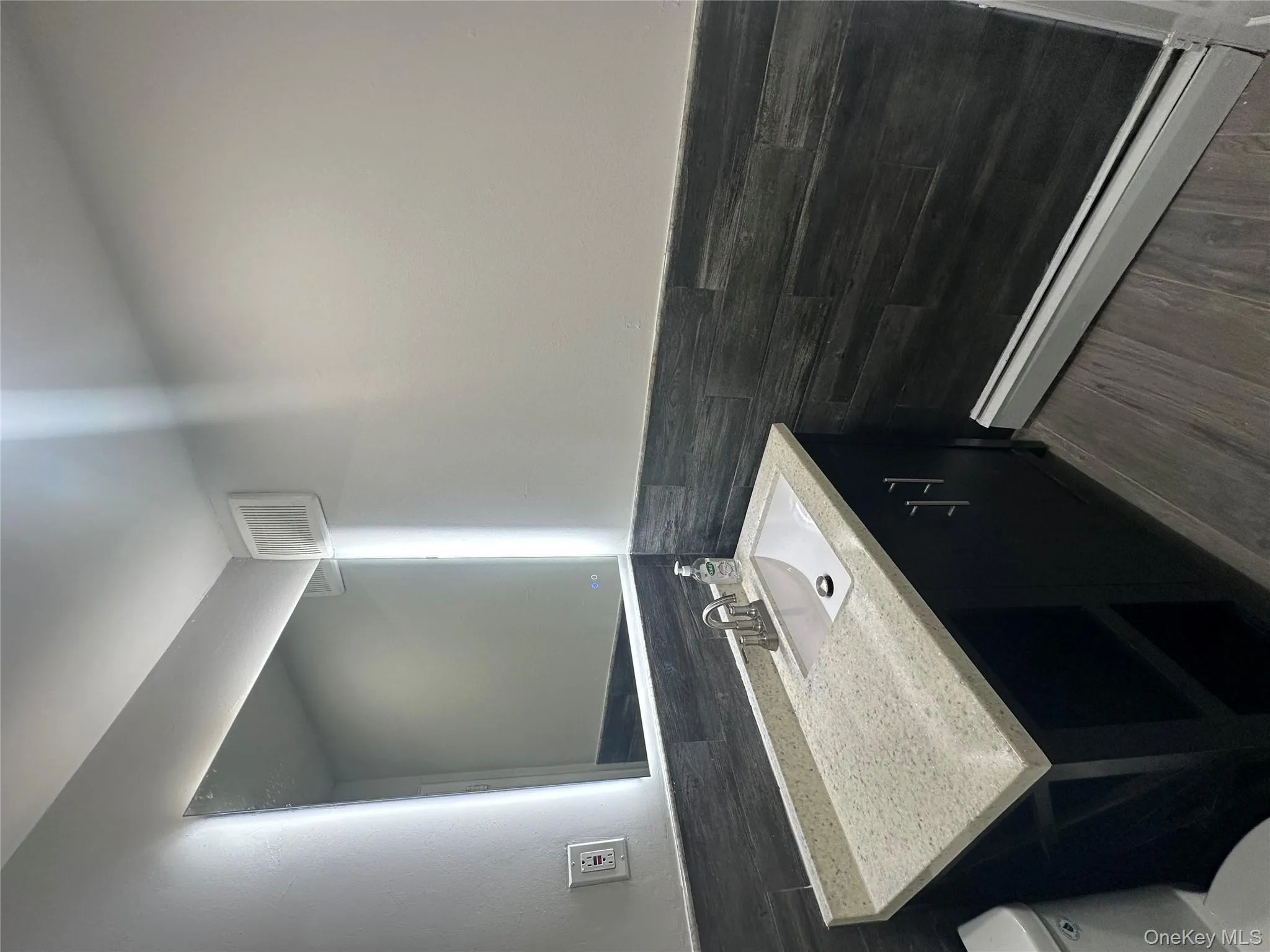 Bathroom featuring wainscoting, vanity, a baseboard radiator, tile walls, and dark wood-style flooring Bathroom featuring wainscoting, vanity, a baseboard radiator, tile walls, and dark wood-style flooring