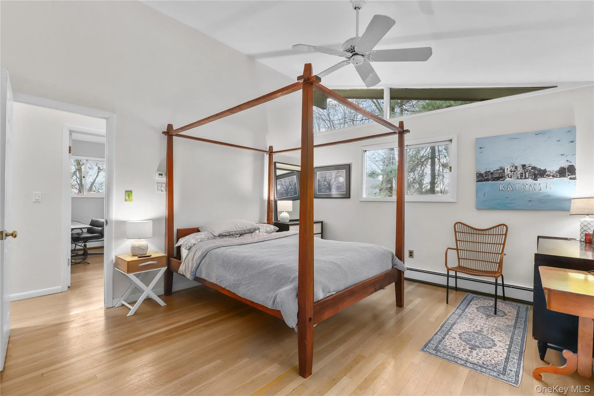 Bedroom featuring multiple windows, baseboard heating, lofted ceiling, a desk, and light wood finished floors Bedroom featuring multiple windows, baseboard heating, lofted ceiling, a desk, and light wood finished floors