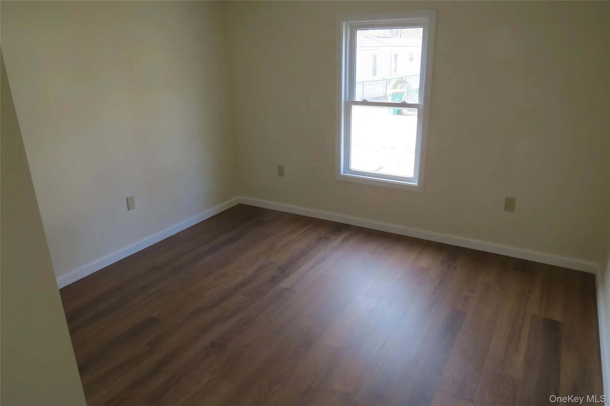 Unfurnished room featuring baseboards and dark wood-type flooring Unfurnished room featuring baseboards and dark wood-type flooring