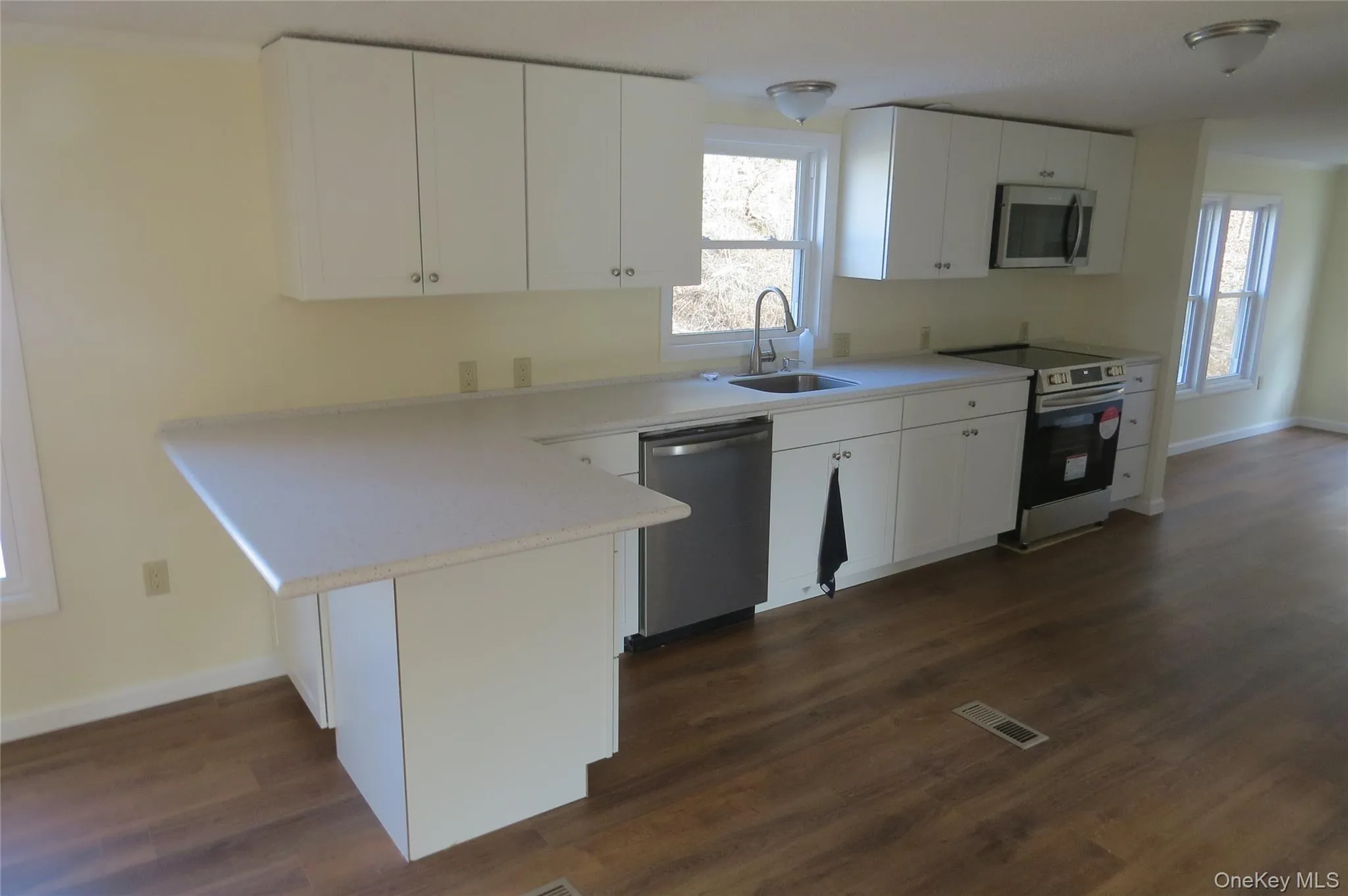 Kitchen with visible vents, appliances with stainless steel finishes, white cabinetry, a sink, and a peninsula Kitchen with visible vents, appliances with stainless steel finishes, white cabinetry, a sink, and a peninsula