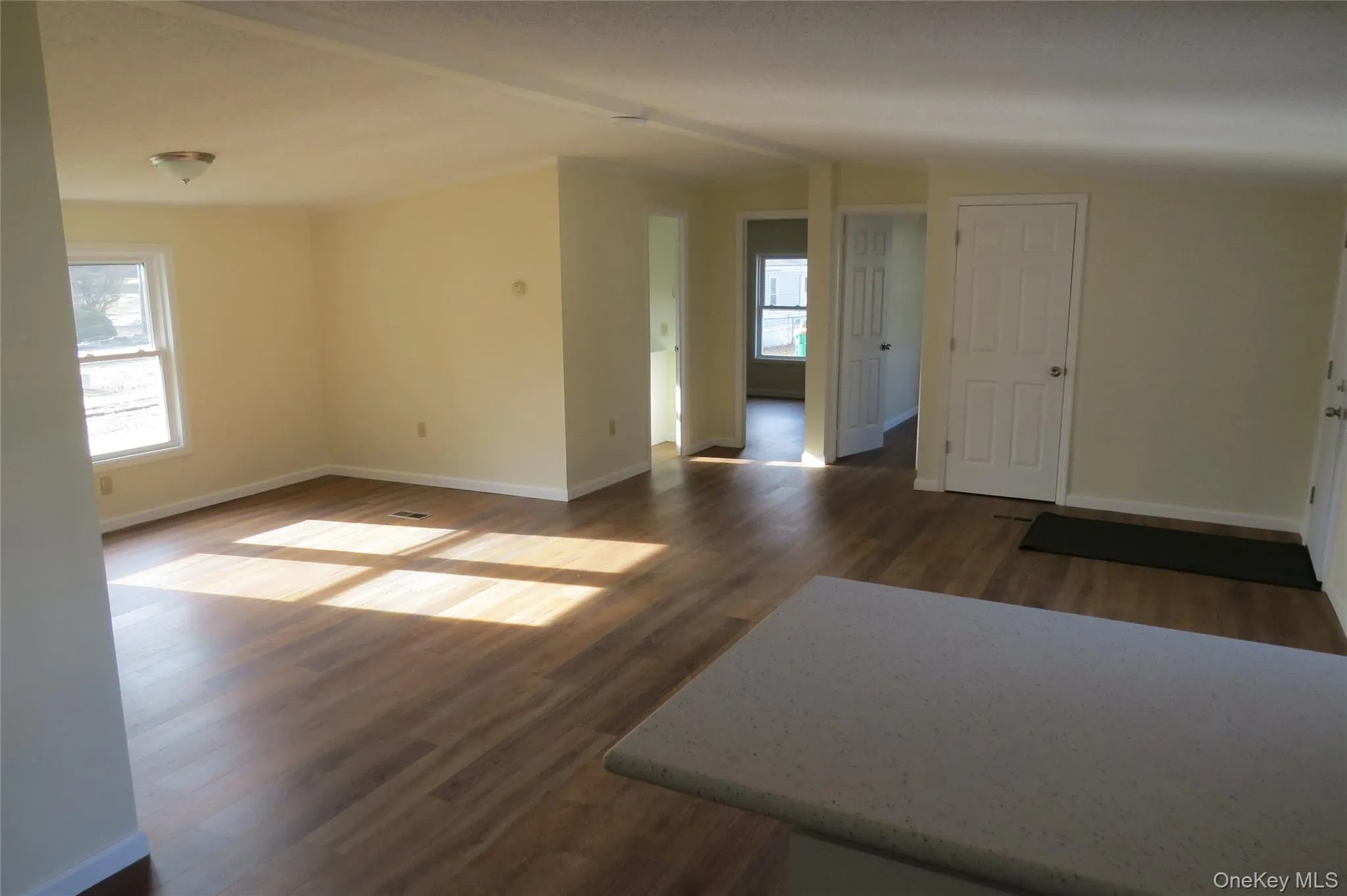 Unfurnished room featuring baseboards, dark wood finished floors, lofted ceiling, and a healthy amount of sunlight Unfurnished room featuring baseboards, dark wood finished floors, lofted ceiling, and a healthy amount of sunlight