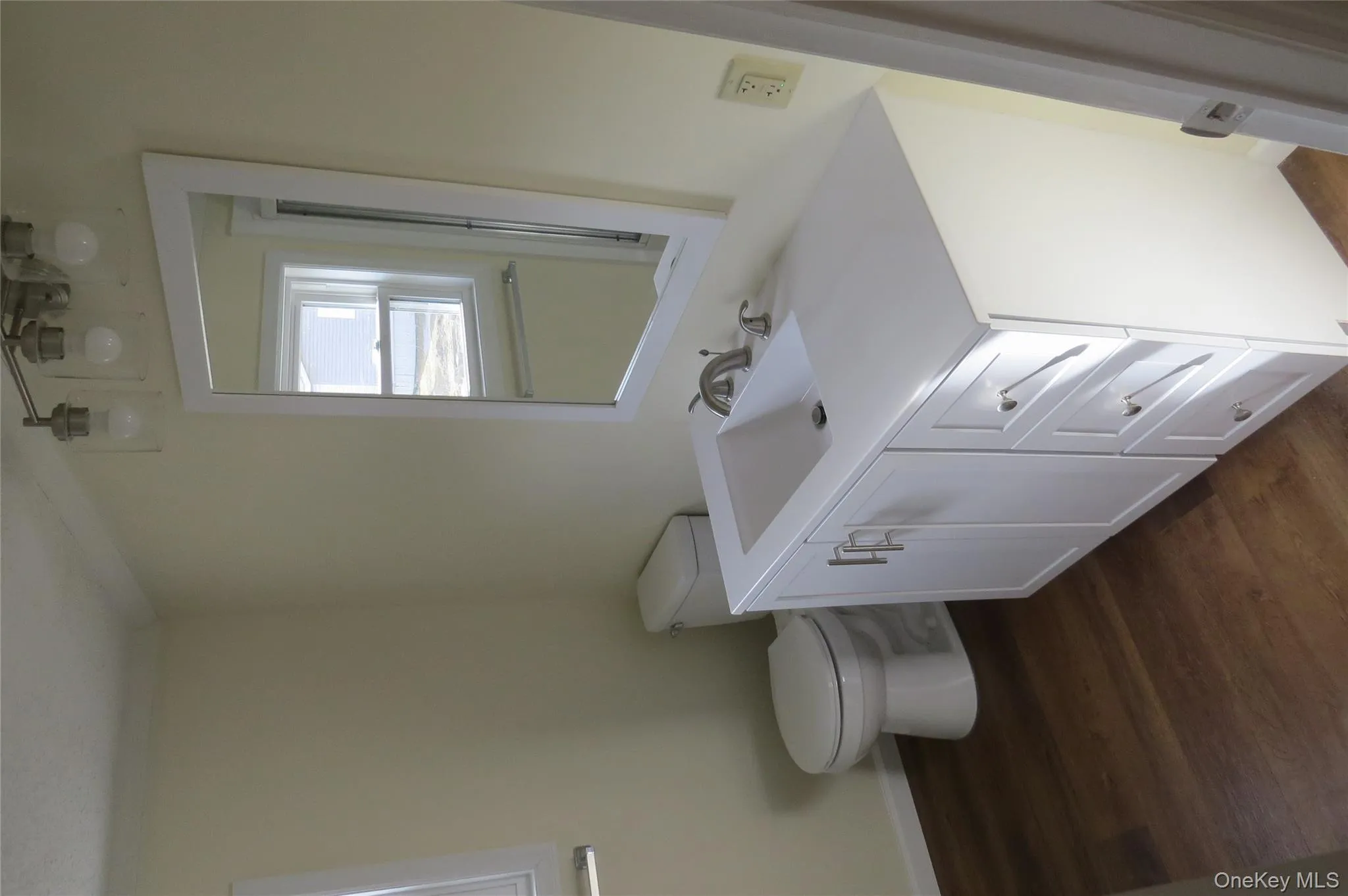 Bathroom featuring crown molding, toilet, vanity, wood finished floors, and baseboards Bathroom featuring crown molding, toilet, vanity, wood finished floors, and baseboards