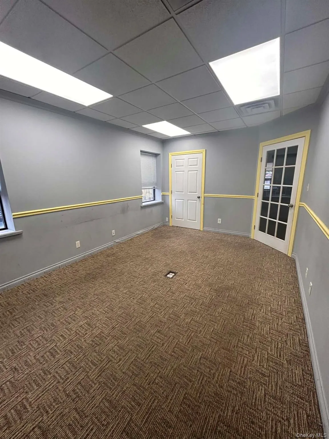 Unfurnished room with a drop ceiling and carpet floors Unfurnished room with a drop ceiling and carpet floors