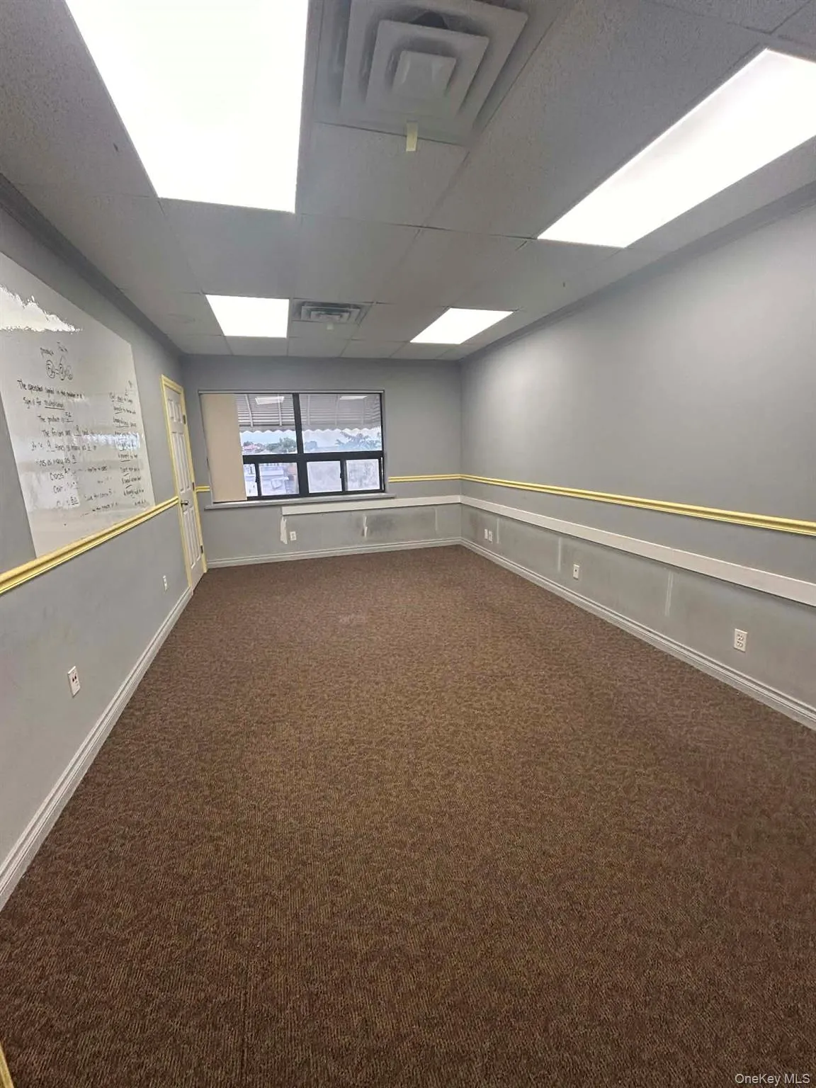 Spare room with a paneled ceiling and dark colored carpet Spare room with a paneled ceiling and dark colored carpet