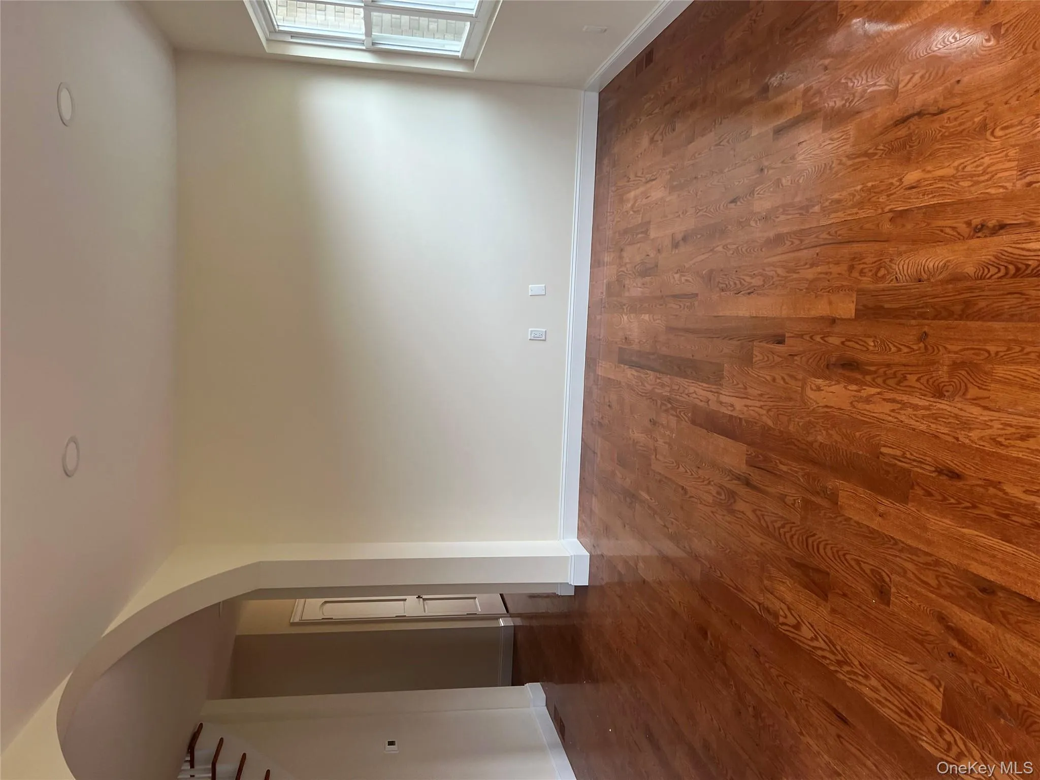Unfurnished room with arched walkways, dark wood-style floors, and stairs Unfurnished room with arched walkways, dark wood-style floors, and stairs