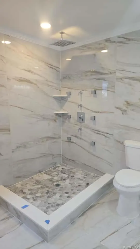 Full bath featuring marble look tiles, a marble finish shower, recessed lighting, crown molding, and tile walls Full bath featuring marble look tiles, a marble finish shower, recessed lighting, crown molding, and tile walls