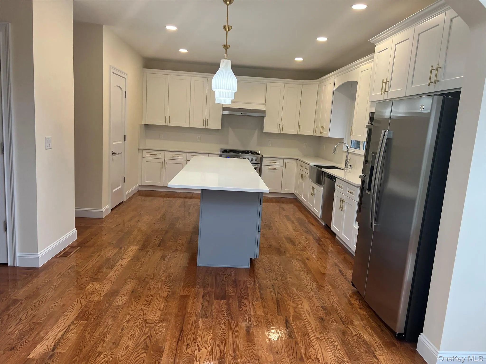 Kitchen featuring stainless steel appliances, white cabinetry, decorative light fixtures, recessed lighting, and a center island Kitchen featuring stainless steel appliances, white cabinetry, decorative light fixtures, recessed lighting, and a center island