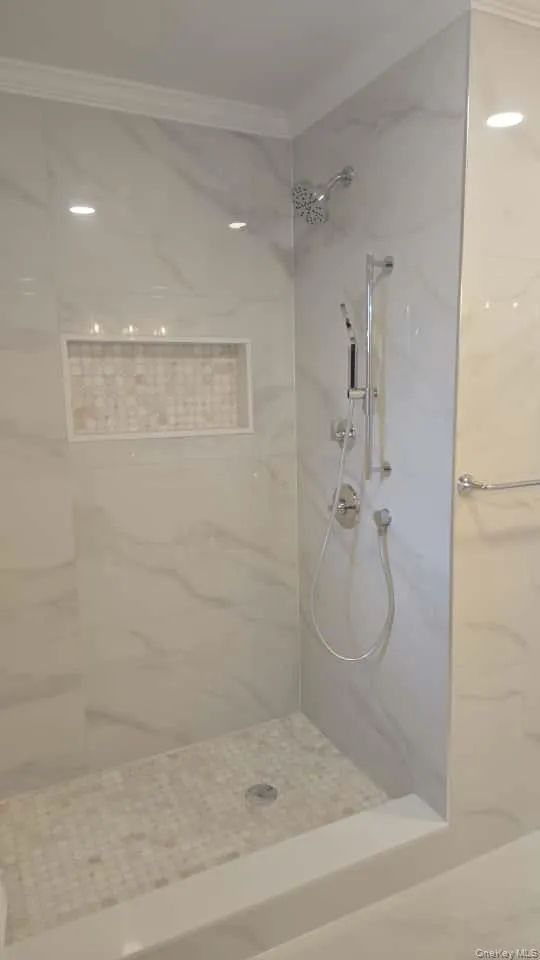 Bathroom with a marble finish shower and ornamental molding Bathroom with a marble finish shower and ornamental molding
