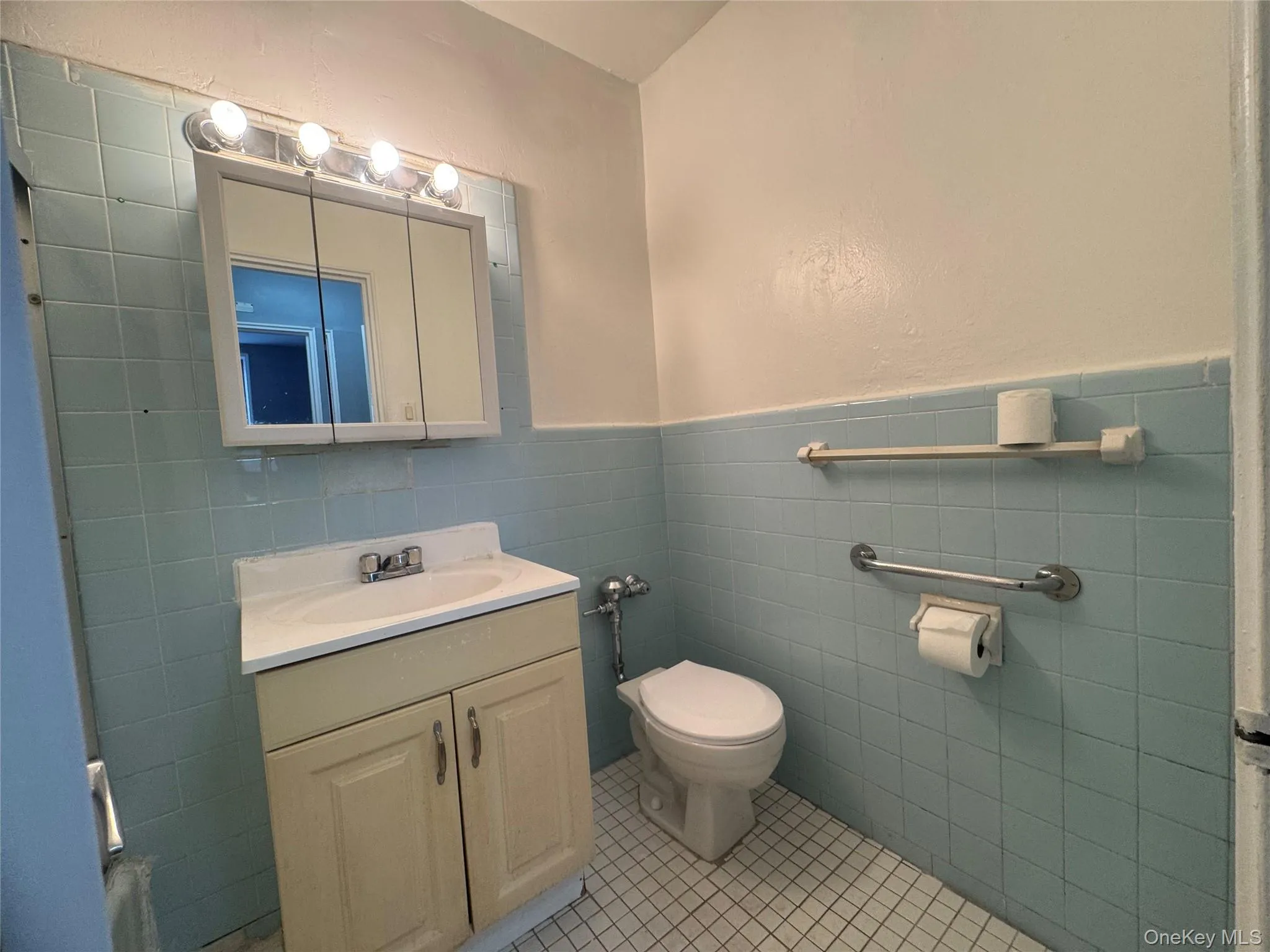 Bathroom featuring vanity, wainscoting, tile walls, and light tile patterned flooring Bathroom featuring vanity, wainscoting, tile walls, and light tile patterned flooring