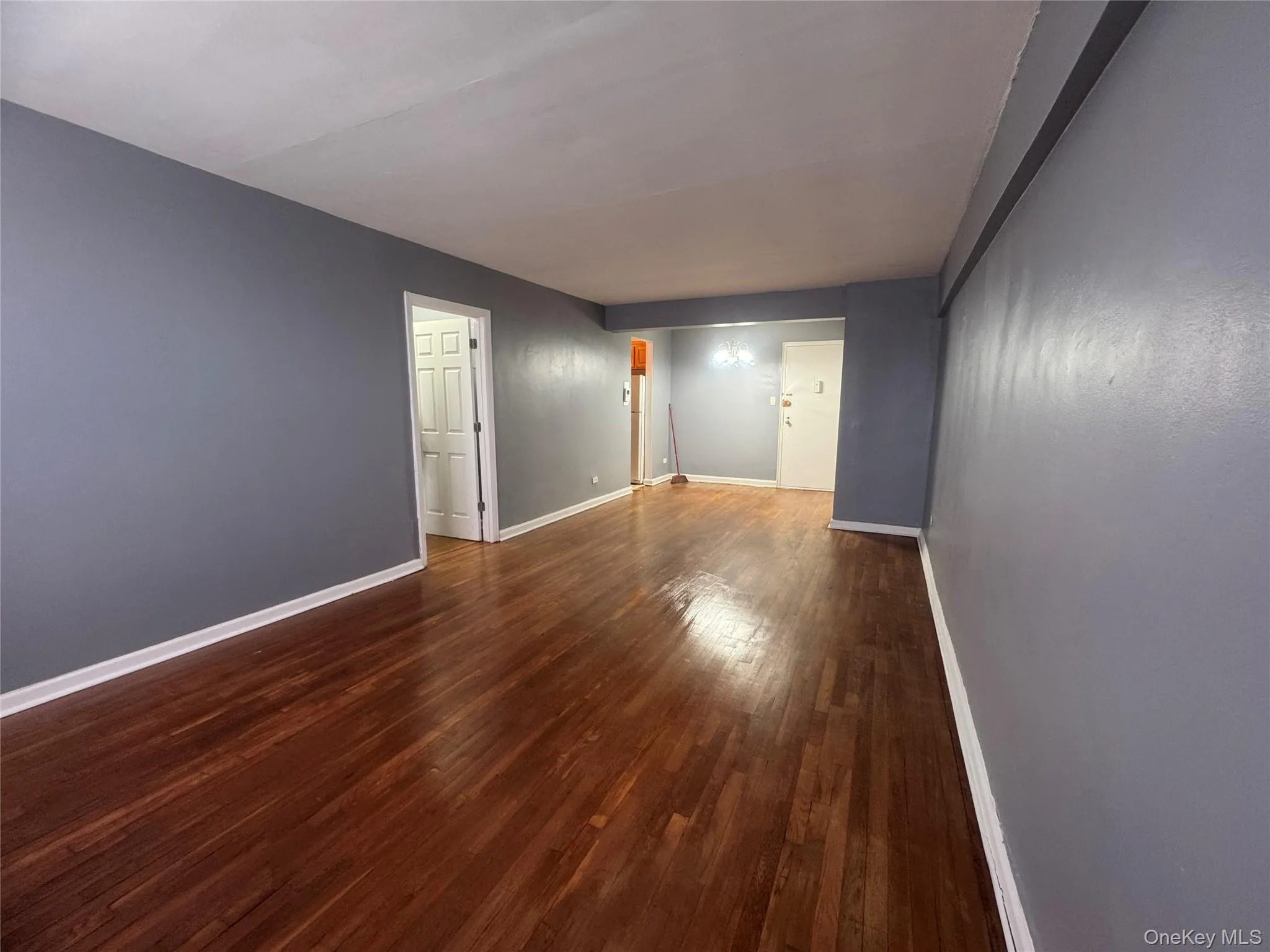 Unfurnished room with dark wood-style floors and baseboards Unfurnished room with dark wood-style floors and baseboards