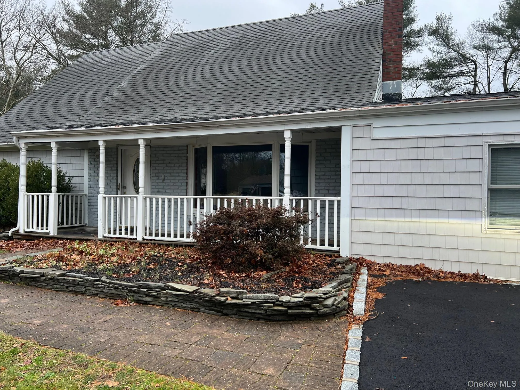 View of front facade with a chimney, covered porch, and a shingled roof View of front facade with a chimney, covered porch, and a shingled roof