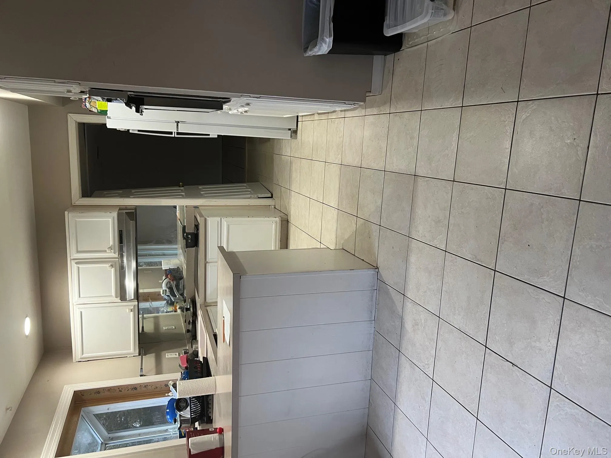 Kitchen featuring white cabinets, a peninsula, light countertops, light tile patterned floors, and ventilation hood Kitchen featuring white cabinets, a peninsula, light countertops, light tile patterned floors, and ventilation hood