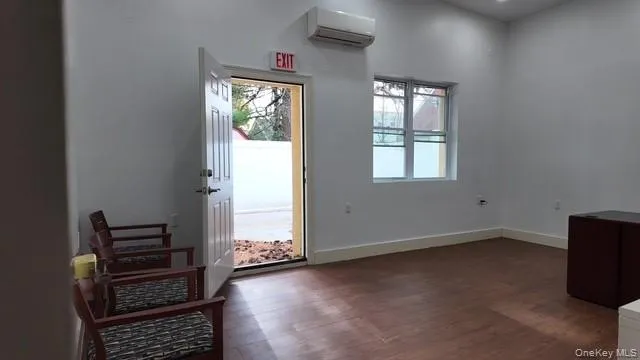 Doorway to outside featuring a wall unit AC and wood finished floors Doorway to outside featuring a wall unit AC and wood finished floors