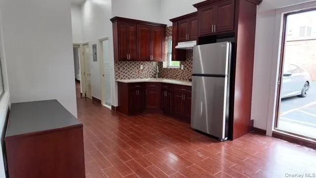 Kitchen with freestanding refrigerator, light countertops, dark brown cabinets, a high ceiling, and dark wood-type flooring Kitchen with freestanding refrigerator, light countertops, dark brown cabinets, a high ceiling, and dark wood-type flooring