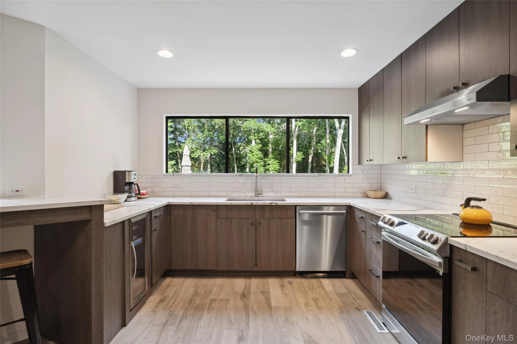 Kitchen with stainless steel appliances, a kitchen bar, a peninsula, light stone counters, and recessed lighting Kitchen with stainless steel appliances, a kitchen bar, a peninsula, light stone counters, and recessed lighting