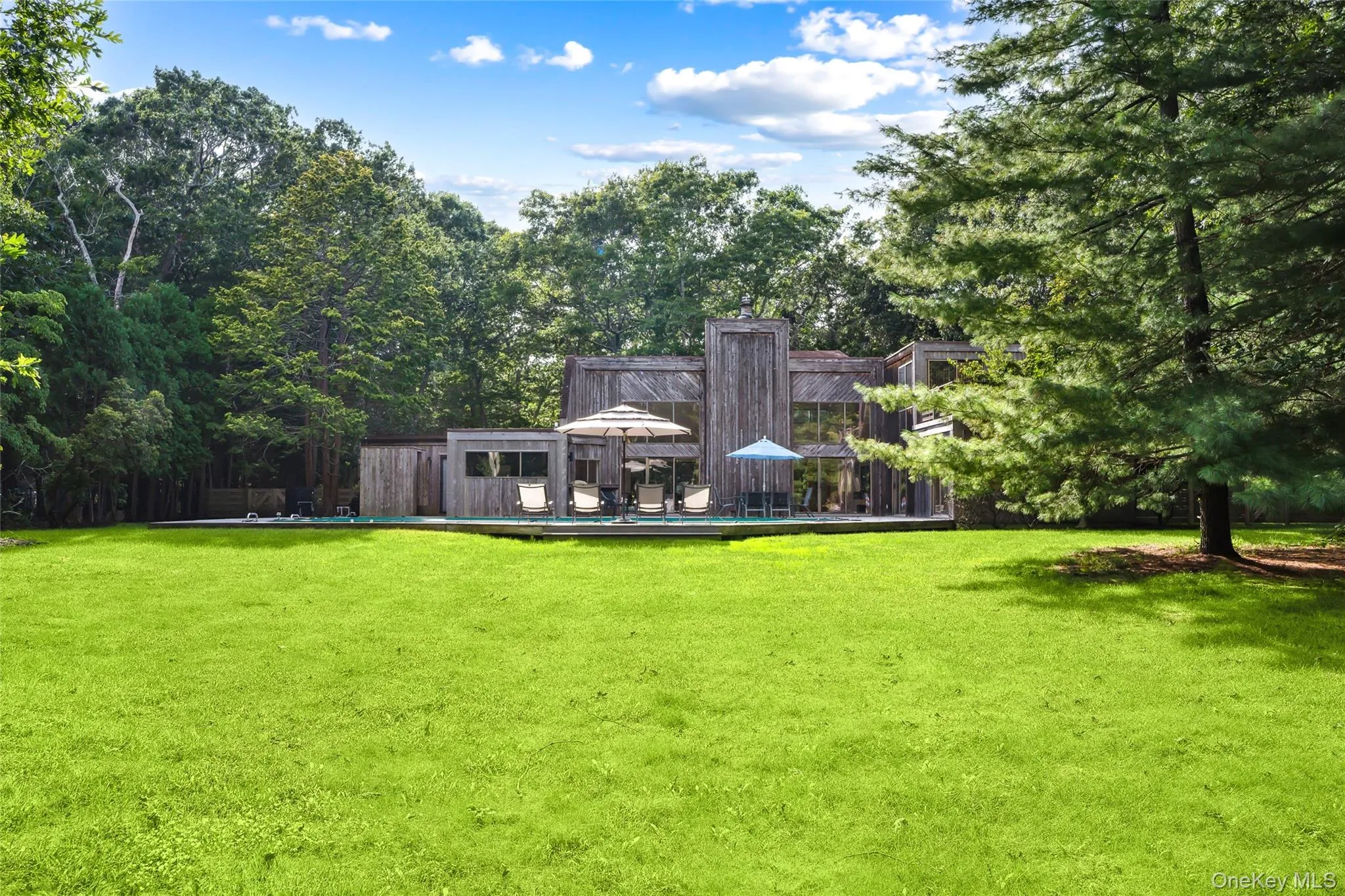 Back of property with a yard, view of wooded area, and a deck Back of property with a yard, view of wooded area, and a deck