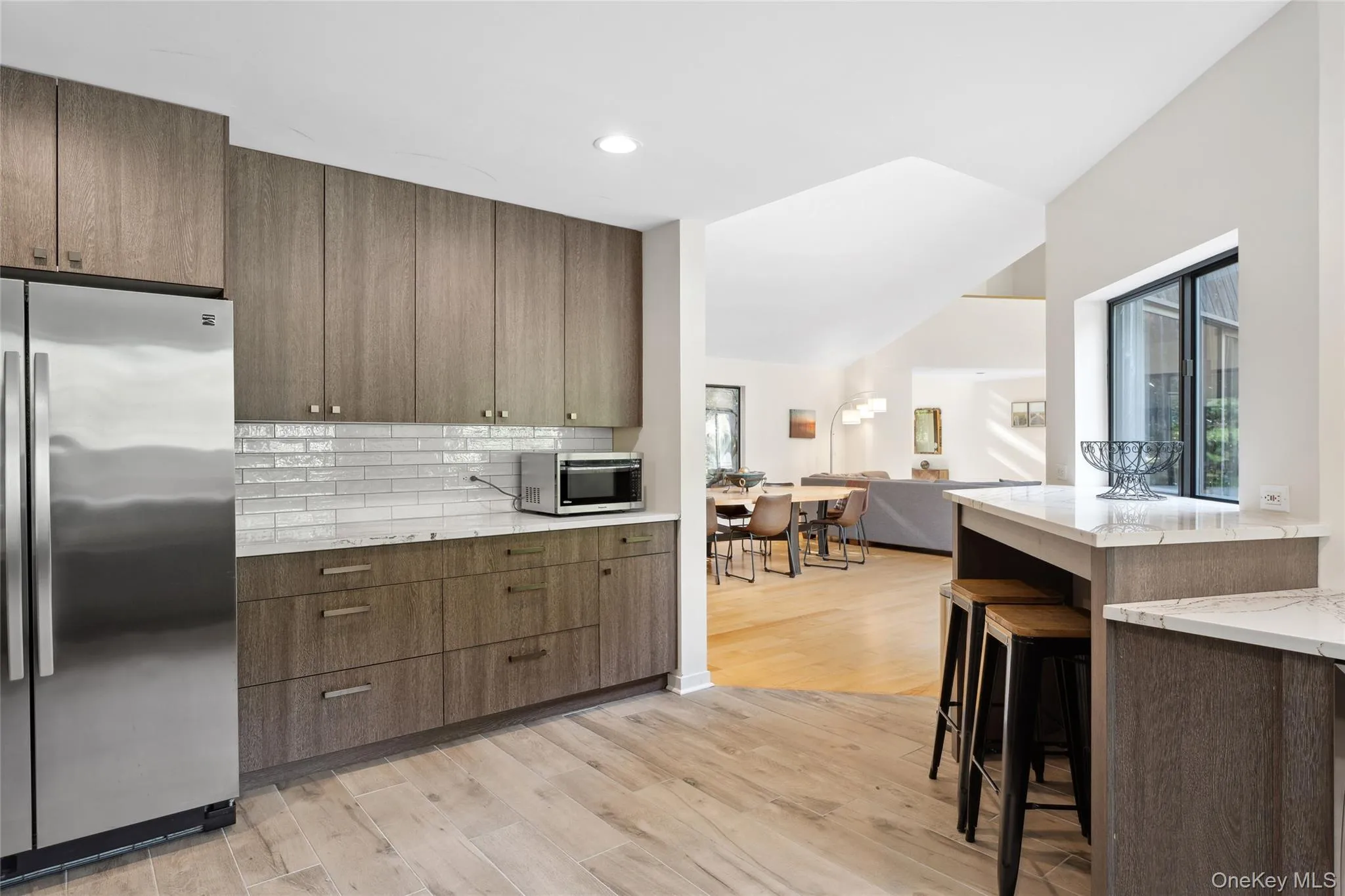 Kitchen with stainless steel appliances, light stone countertops, decorative backsplash, light wood-style floors, and open floor plan Kitchen with stainless steel appliances, light stone countertops, decorative backsplash, light wood-style floors, and open floor plan