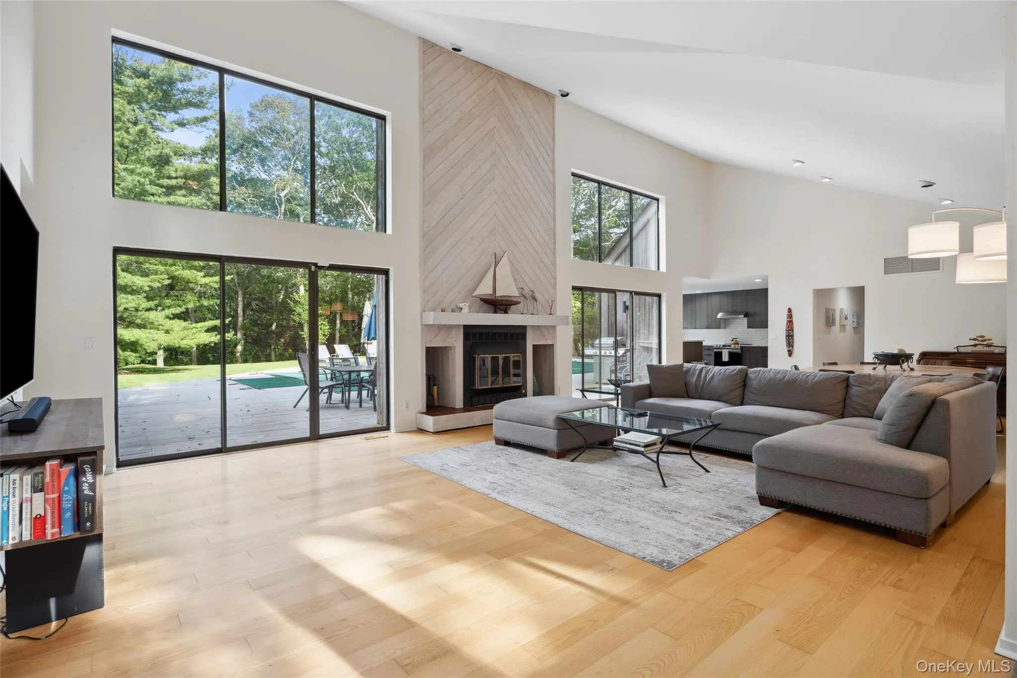 Living room with a towering ceiling, light wood-style floors, and a large fireplace Living room with a towering ceiling, light wood-style floors, and a large fireplace