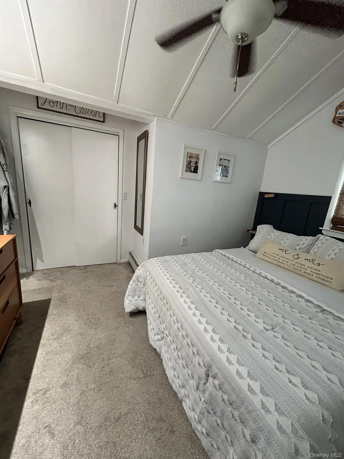 Carpeted bedroom with ceiling fan, lofted ceiling, a closet, and a baseboard radiator Carpeted bedroom with ceiling fan, lofted ceiling, a closet, and a baseboard radiator